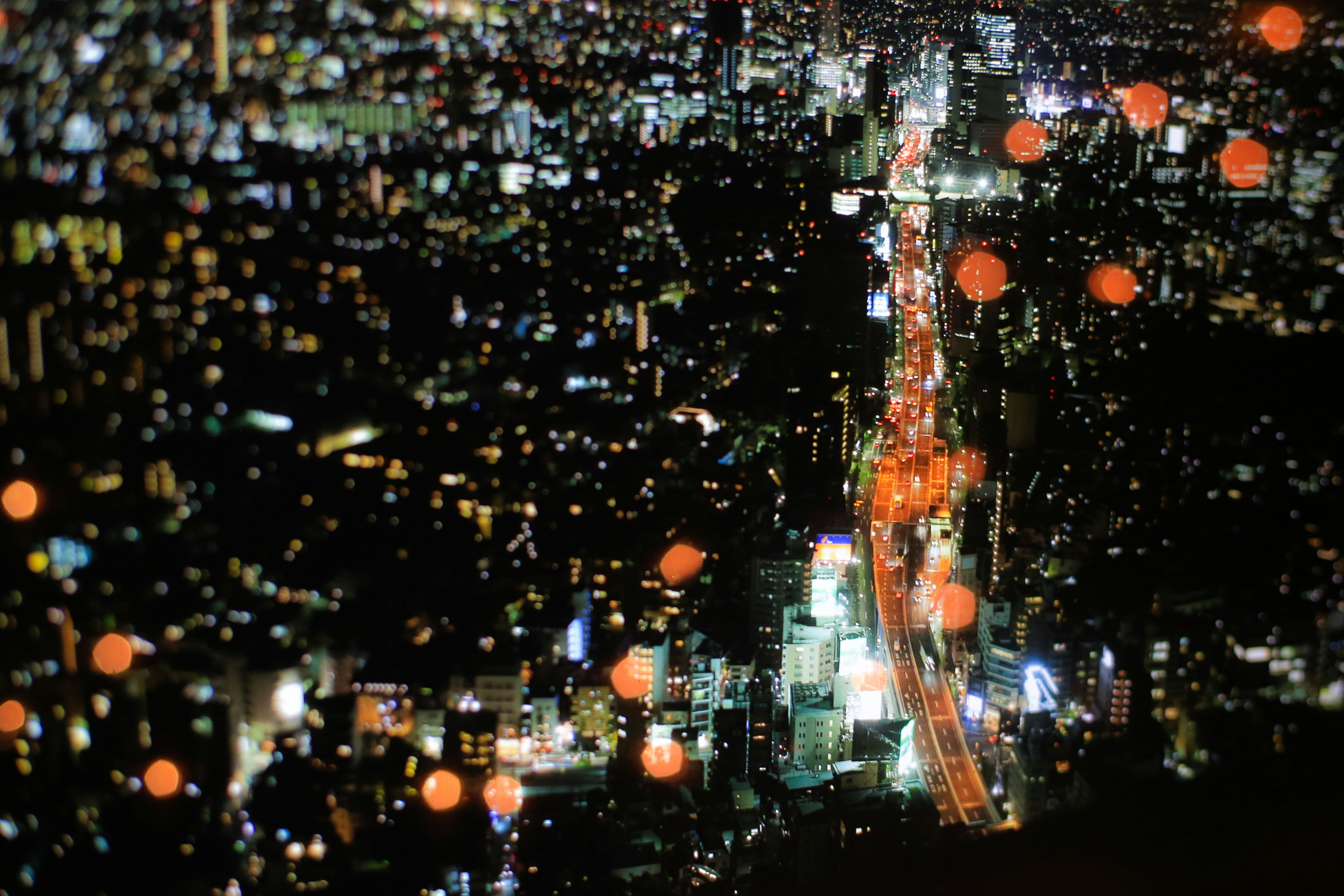 Vista aerea di Tokyo di notte con edifici illuminati e una strada principale