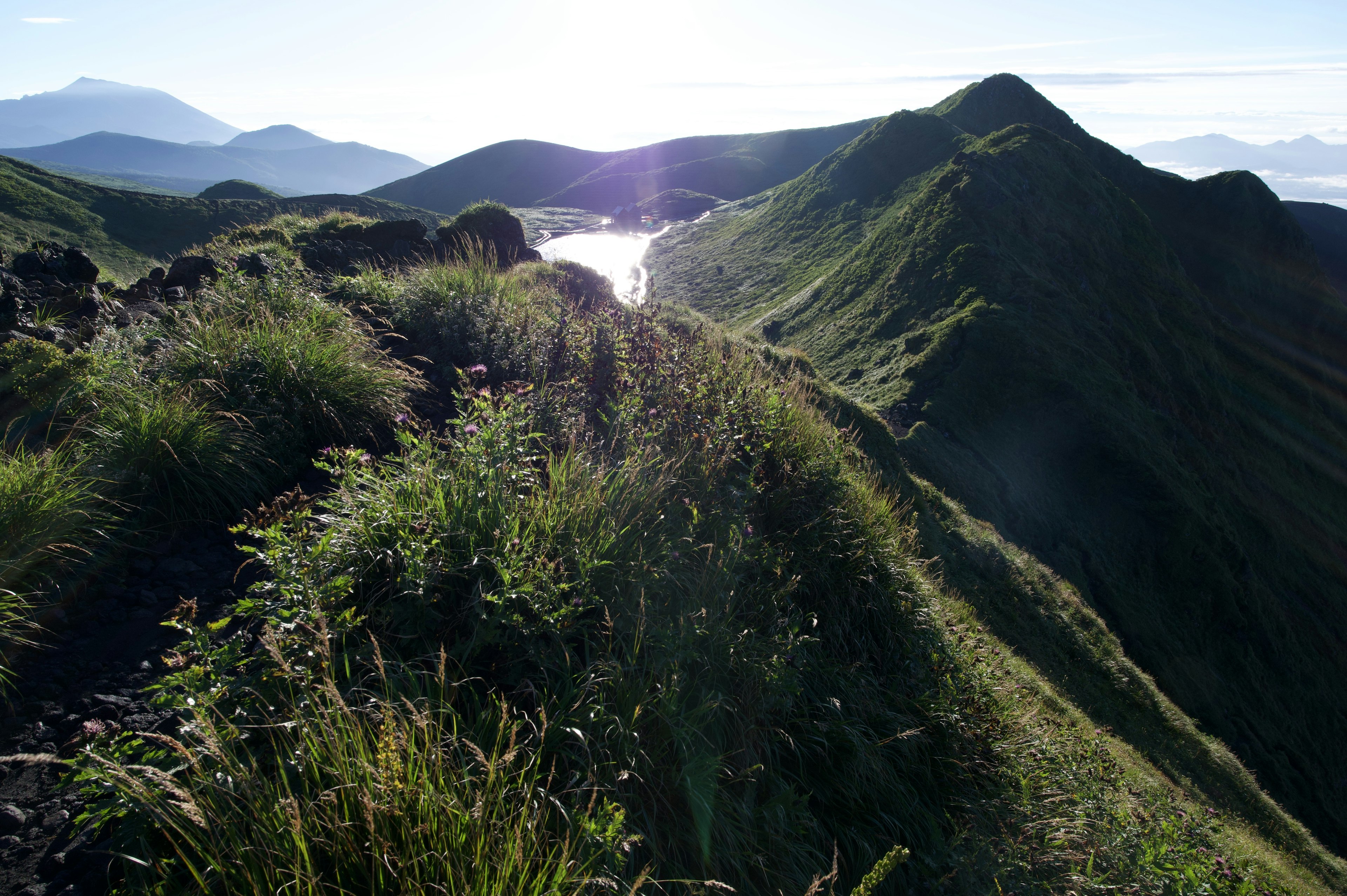 Crestas de montaña verde con un lago al fondo