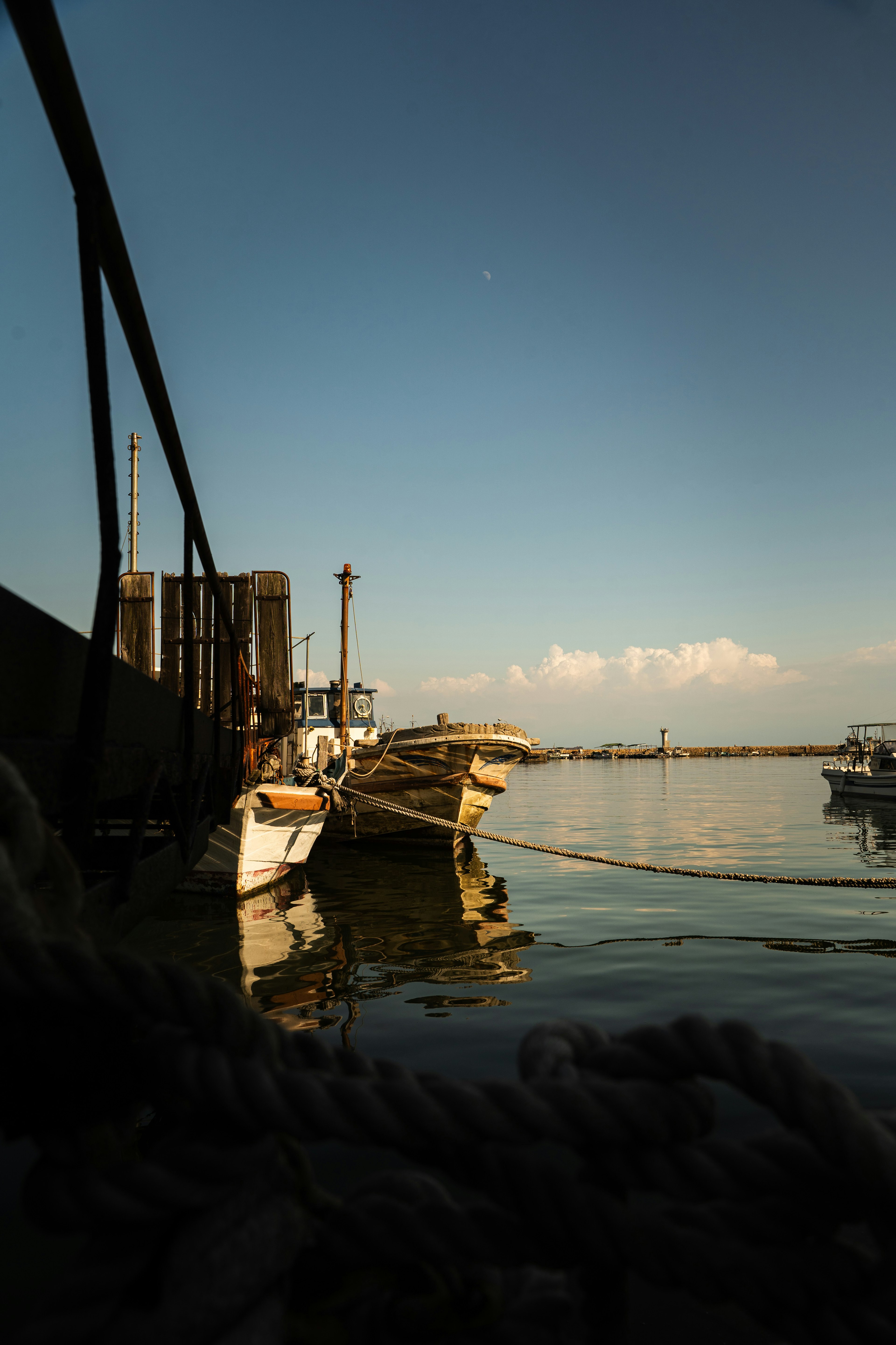 Barche riflesse su acqua calma sotto un cielo azzurro