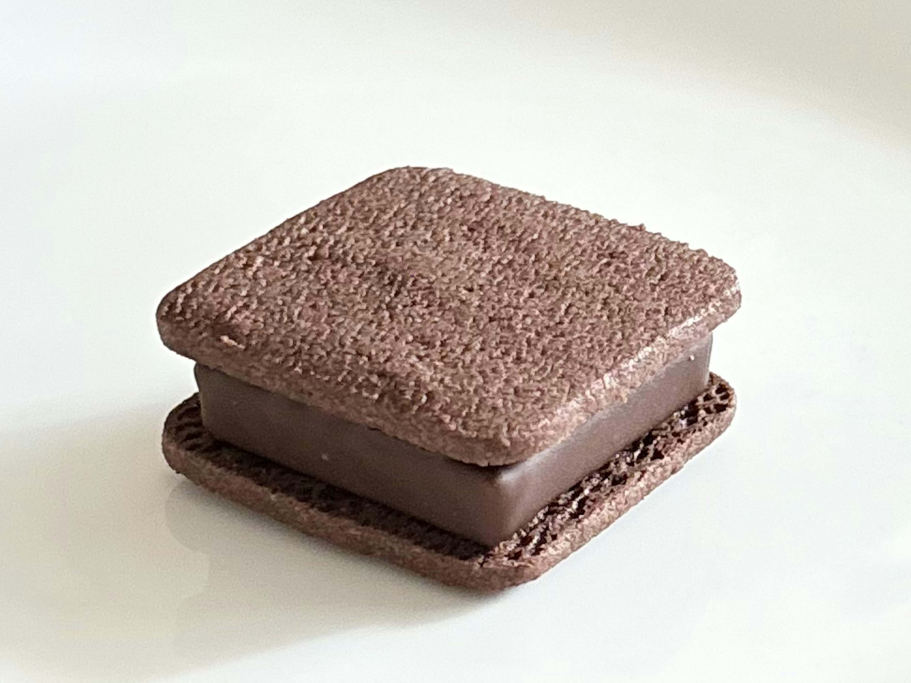 Chocolate sandwich cookie with a textured brownie-like top and bottom layer