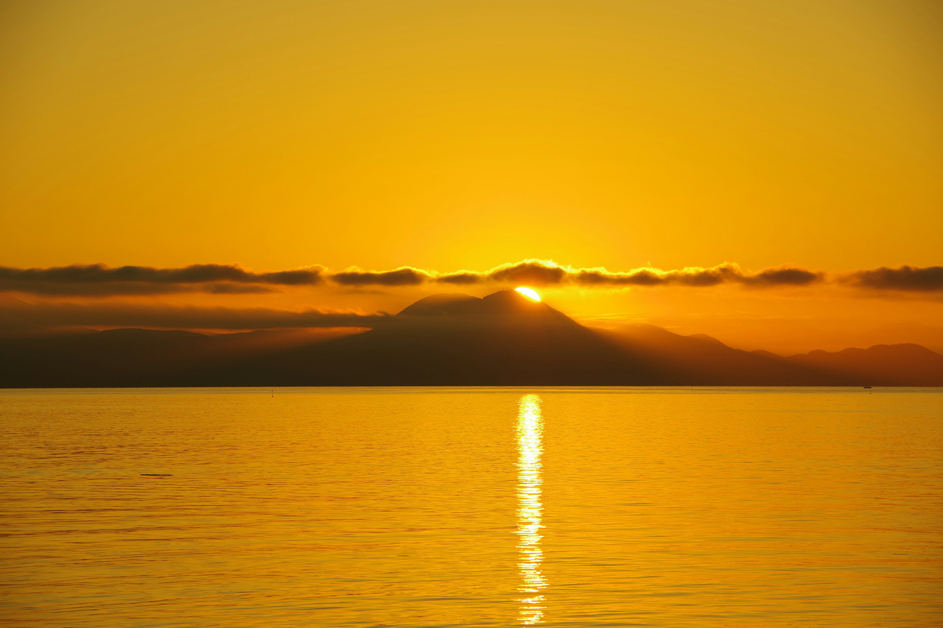 Stupendo tramonto su una montagna con cielo arancione e superficie d'acqua riflettente