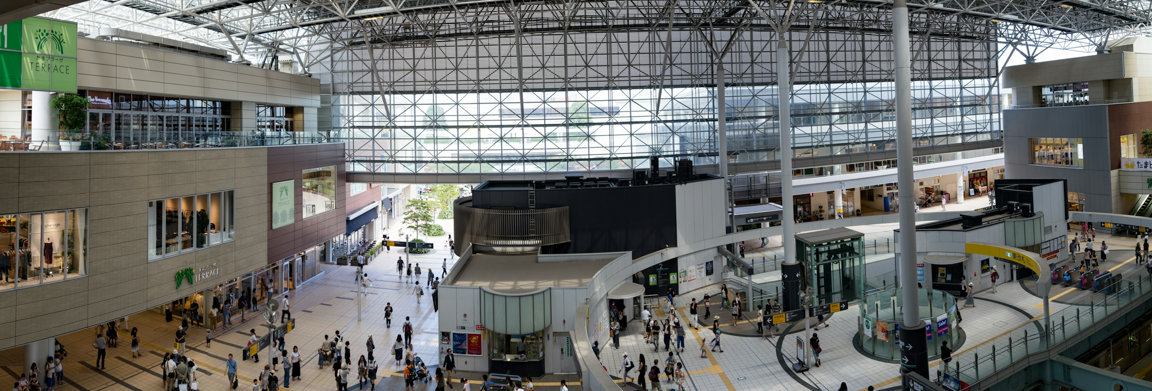 Spacious modern airport terminal interior with many people and light streaming through glass ceiling