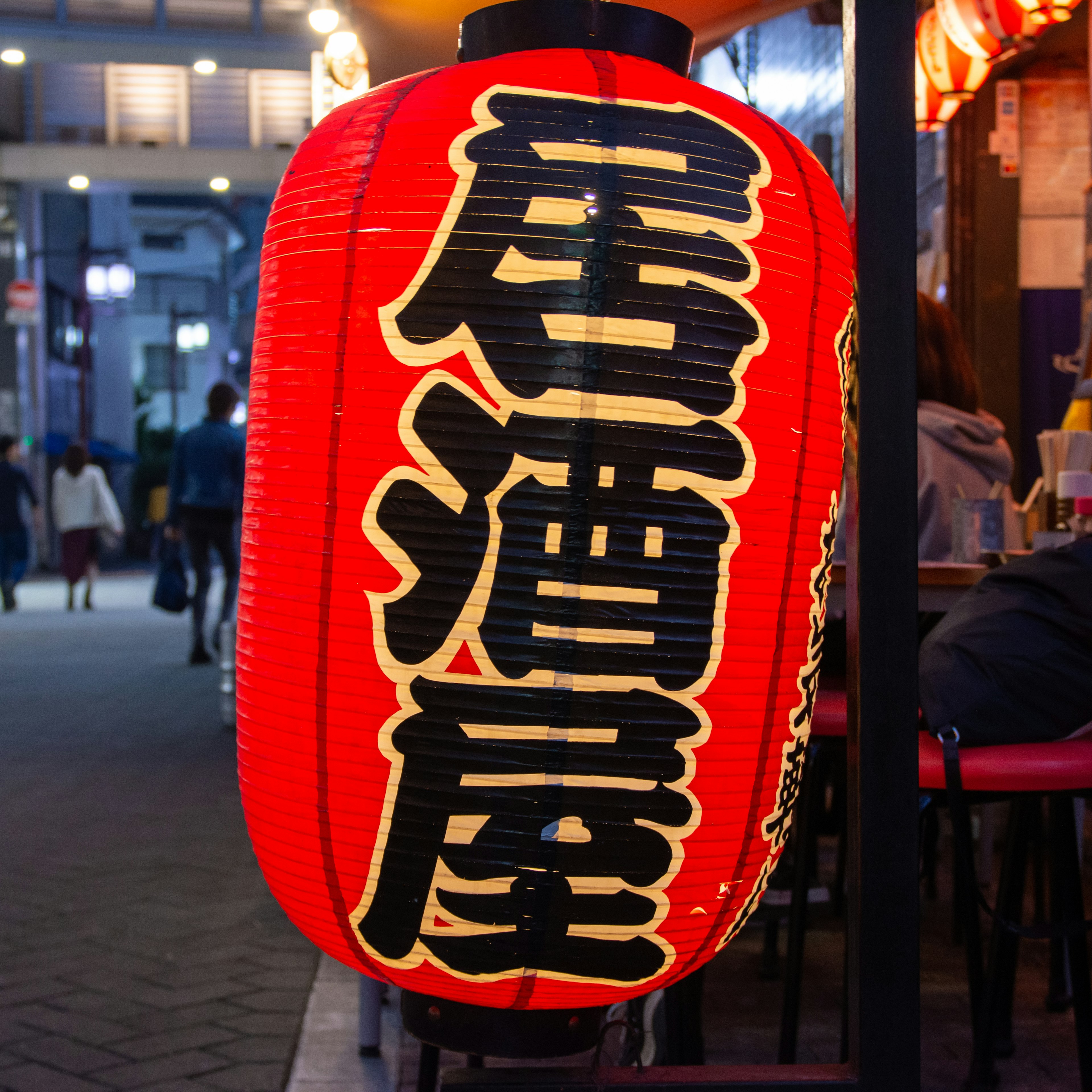 Red lantern with black lettering in a street food scene