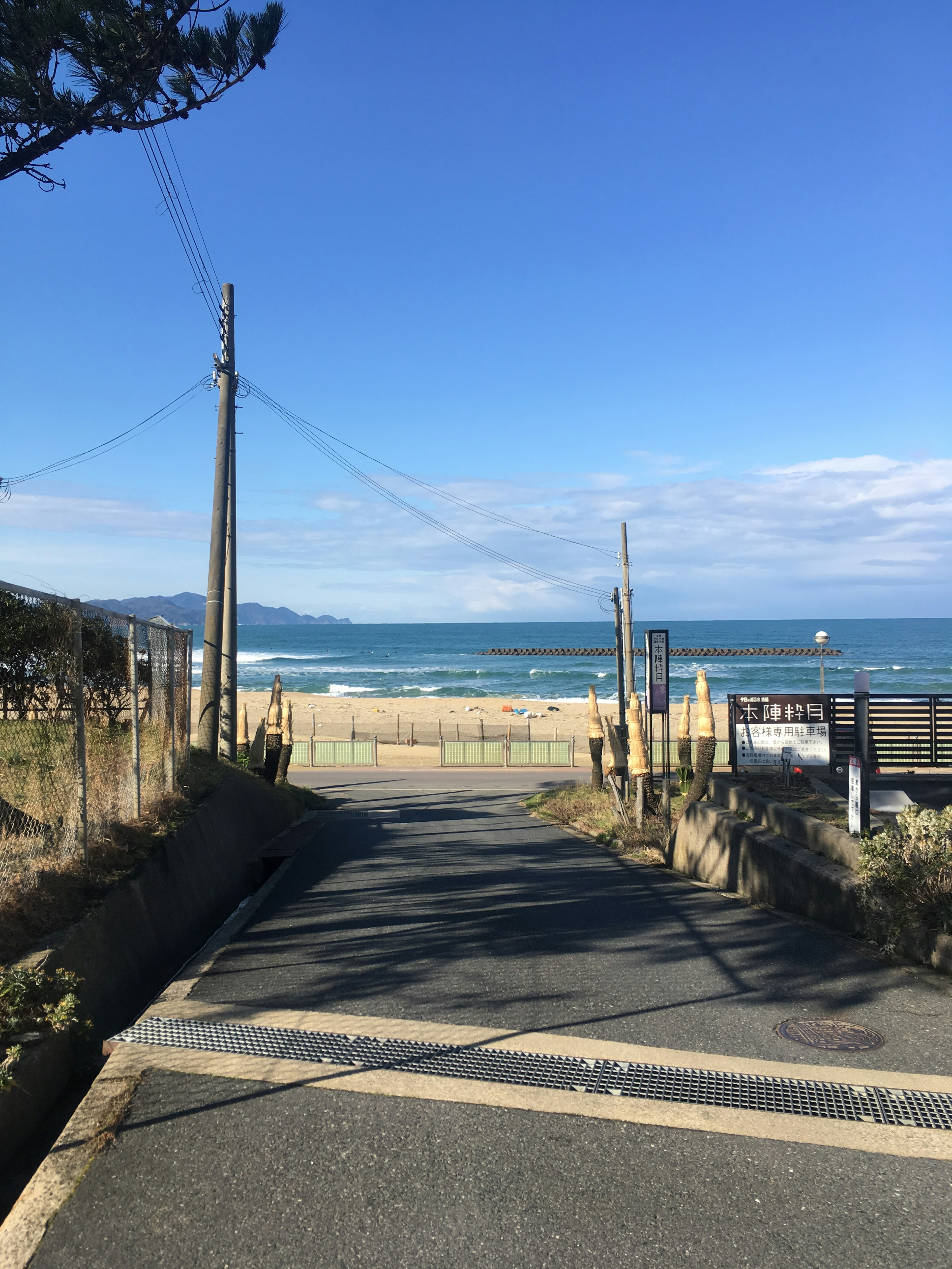 Weg, der zum Strand unter einem klaren blauen Himmel mit sanften Wellen führt