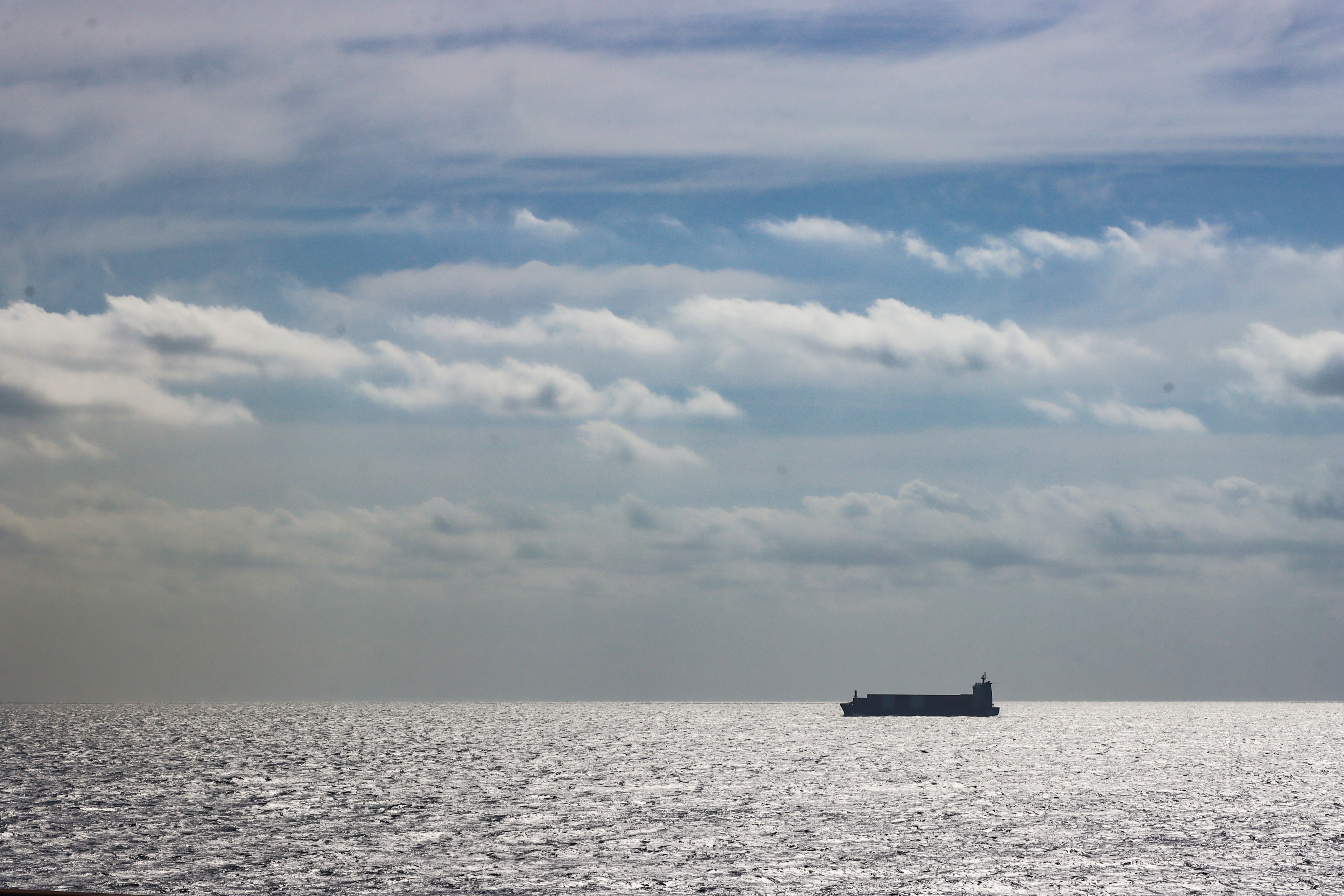 Un barco flotando en un mar brillante bajo un cielo claro