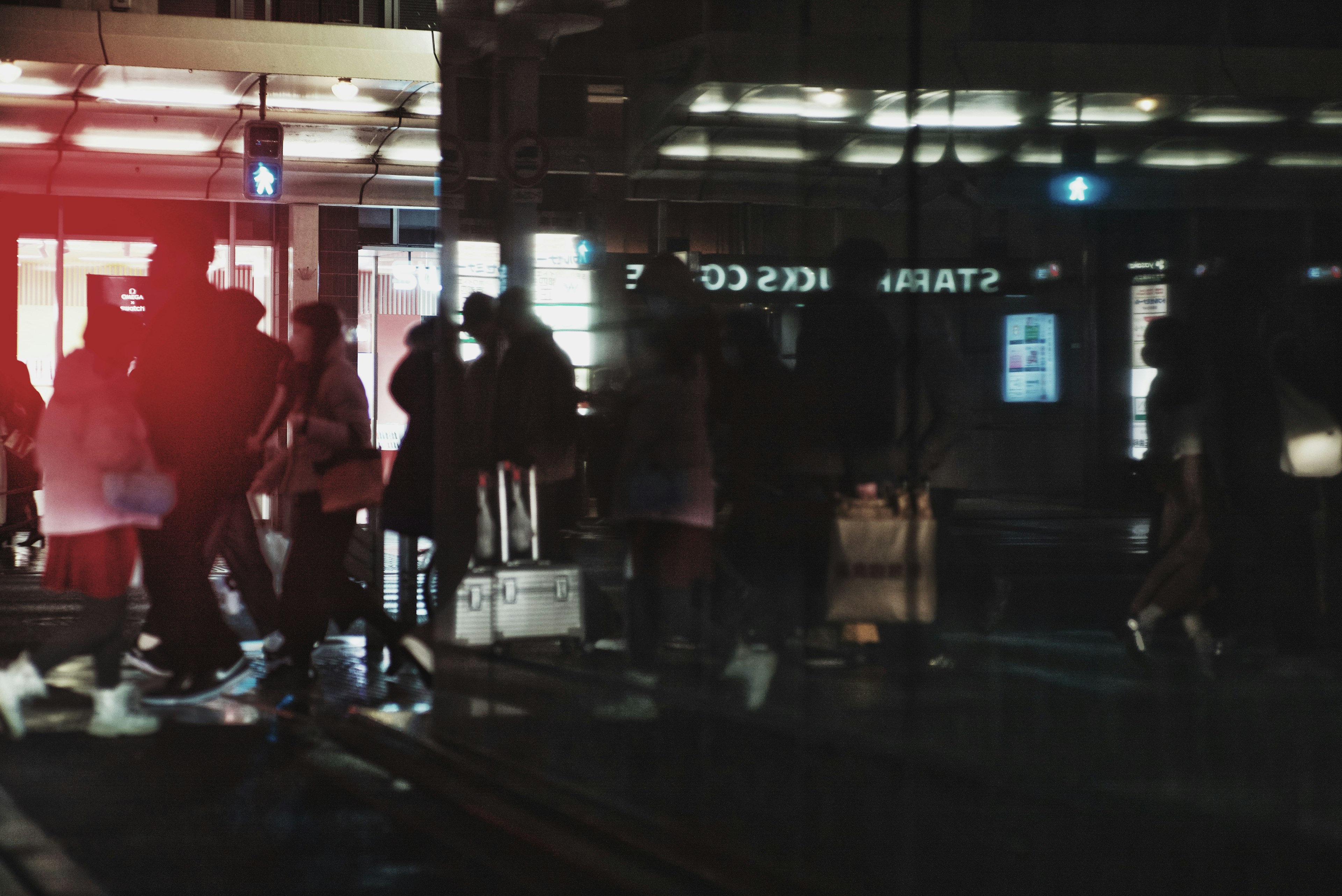 Escena de personas caminando por la ciudad de noche con luces y colores reflectantes