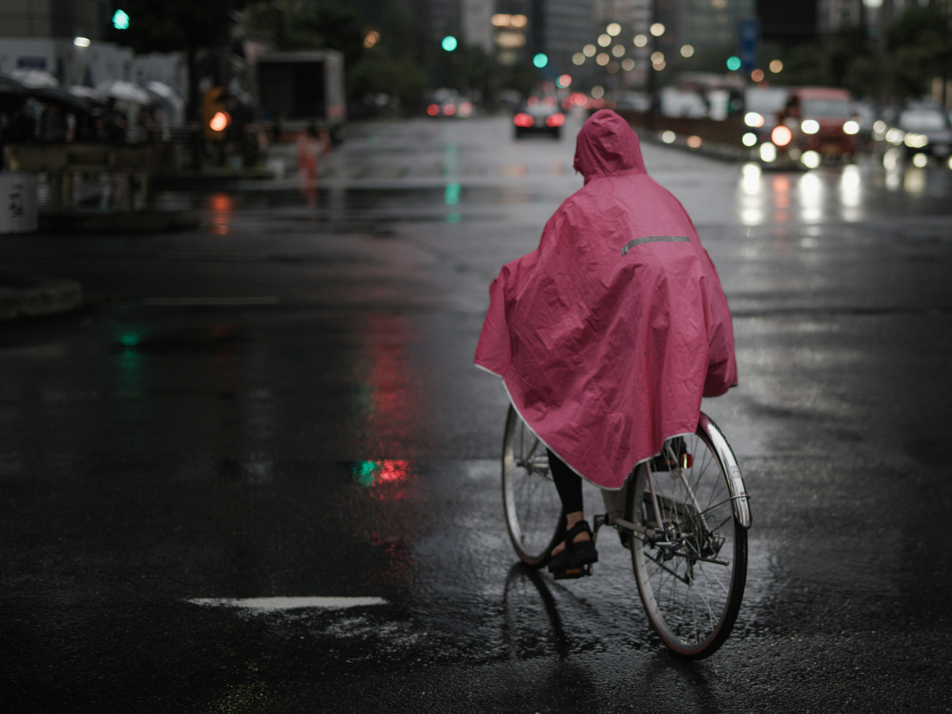 穿着粉色雨衣的人在雨中骑自行车