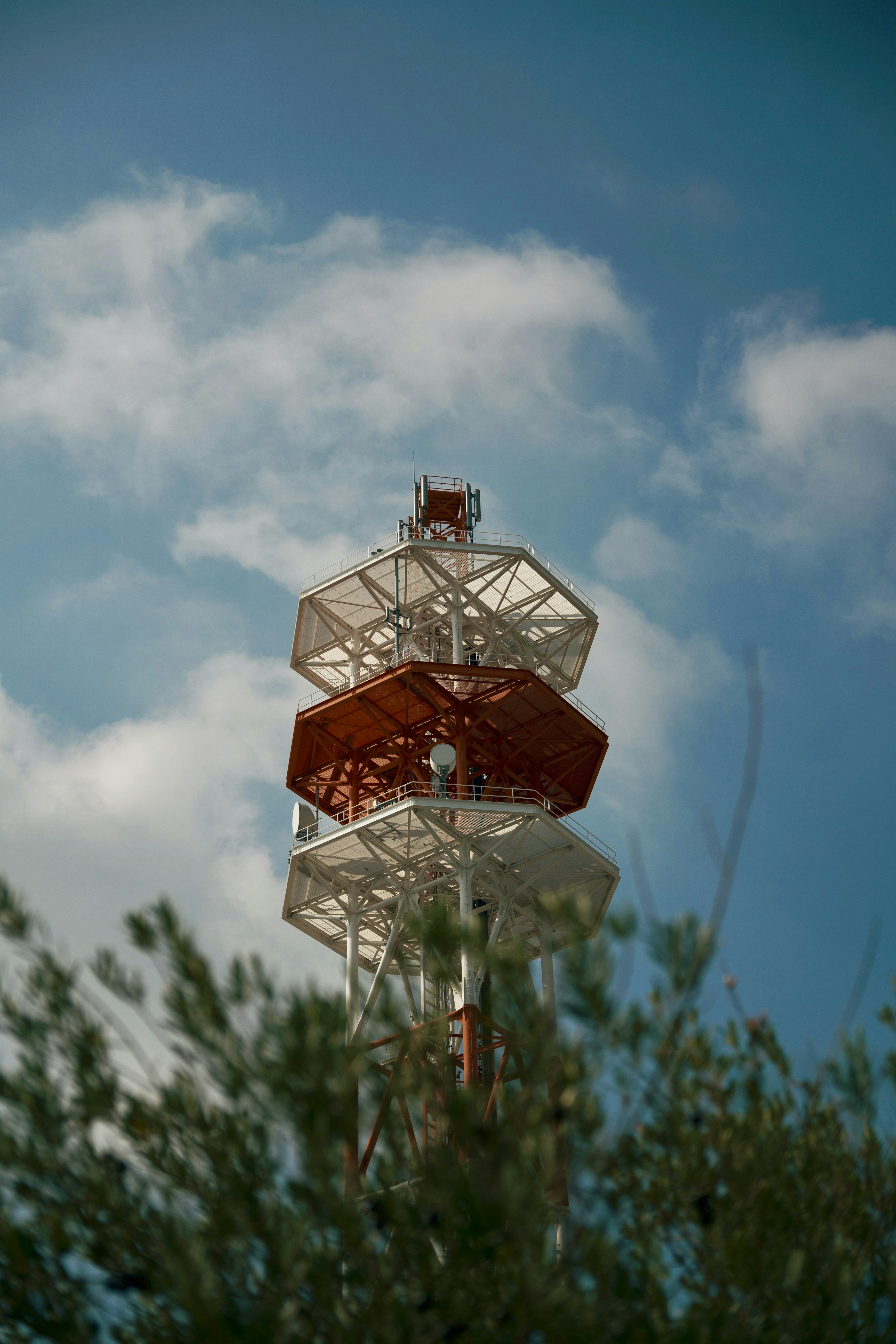 Close-up of a red and white communication tower against a blue sky