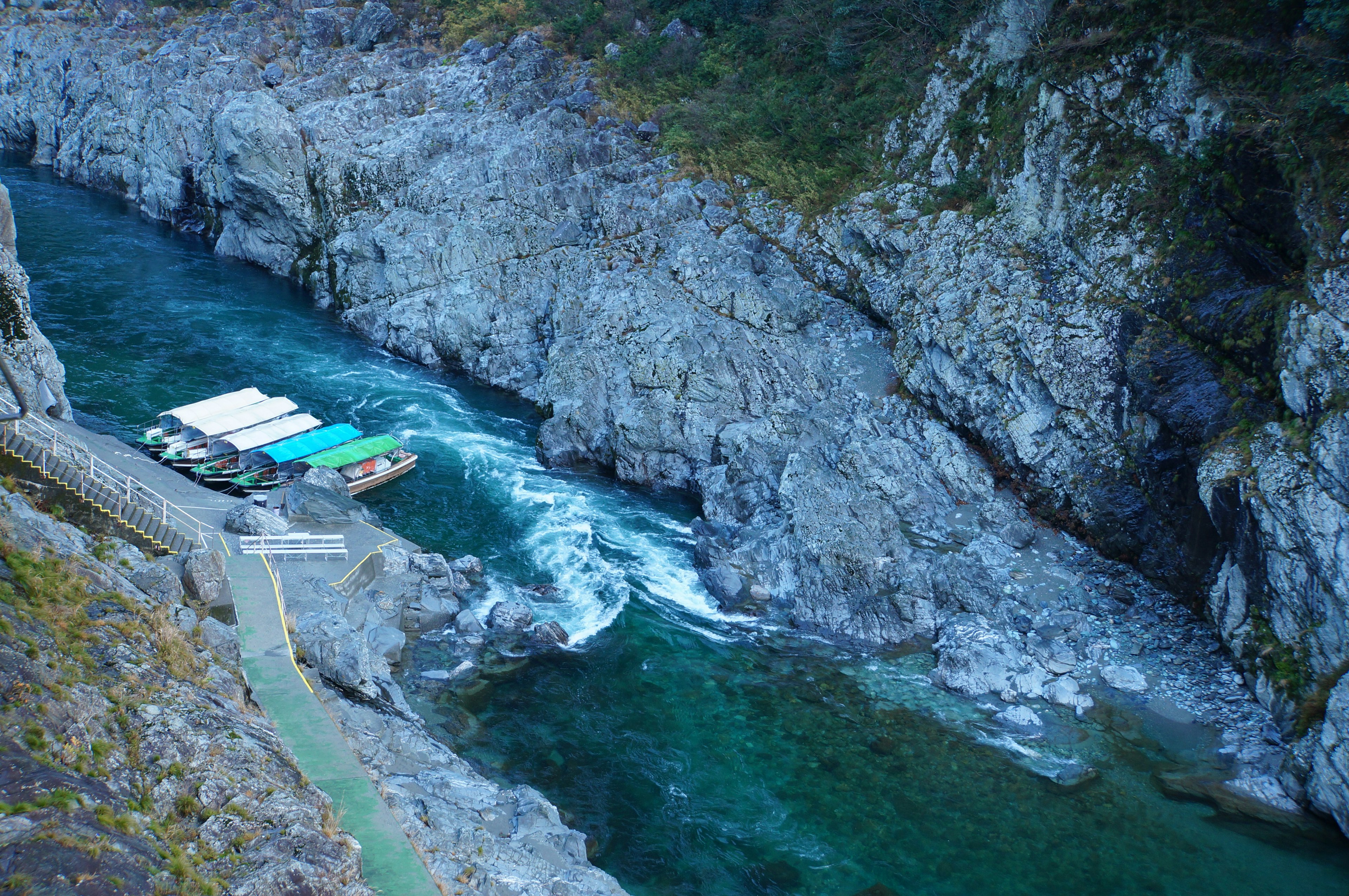 Vista panoramica di un piccolo molo per barche circondato da acqua blu e scogliere rocciose