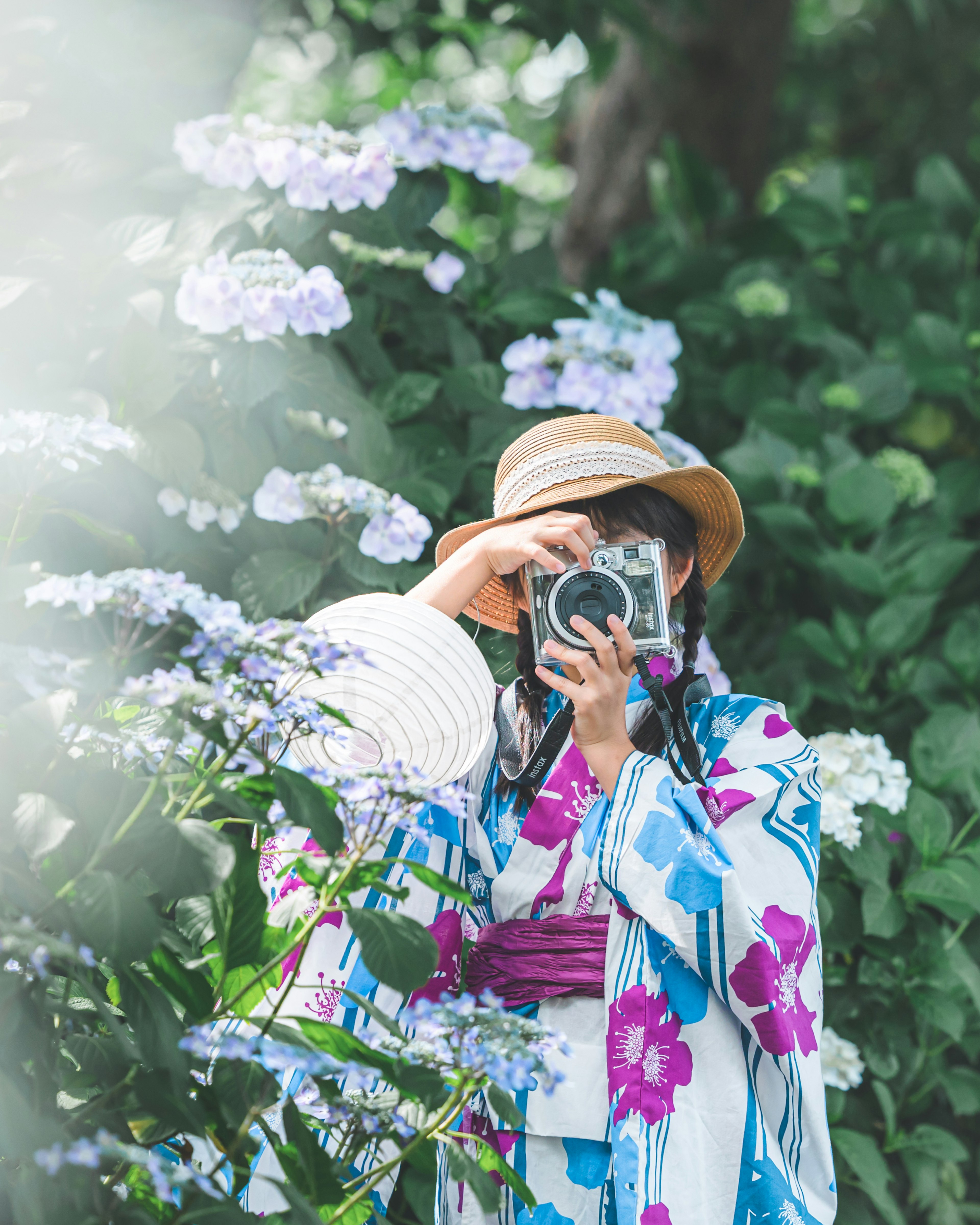 Frau im traditionellen Kimono, die eine Kamera hält, umgeben von Blumen