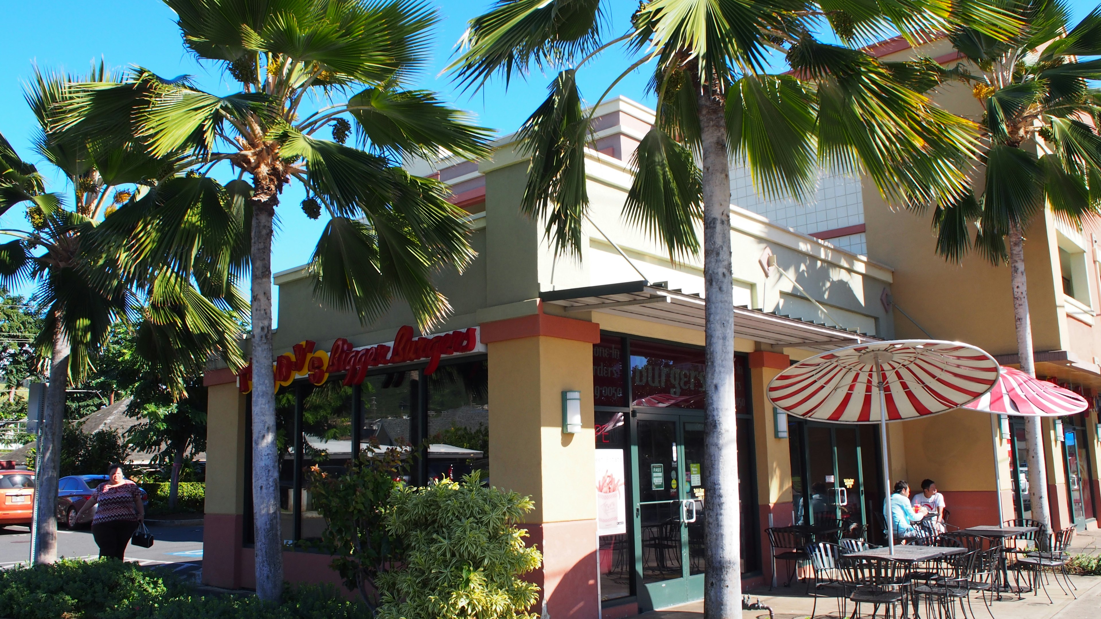 Colorful restaurant exterior with palm trees under a bright blue sky