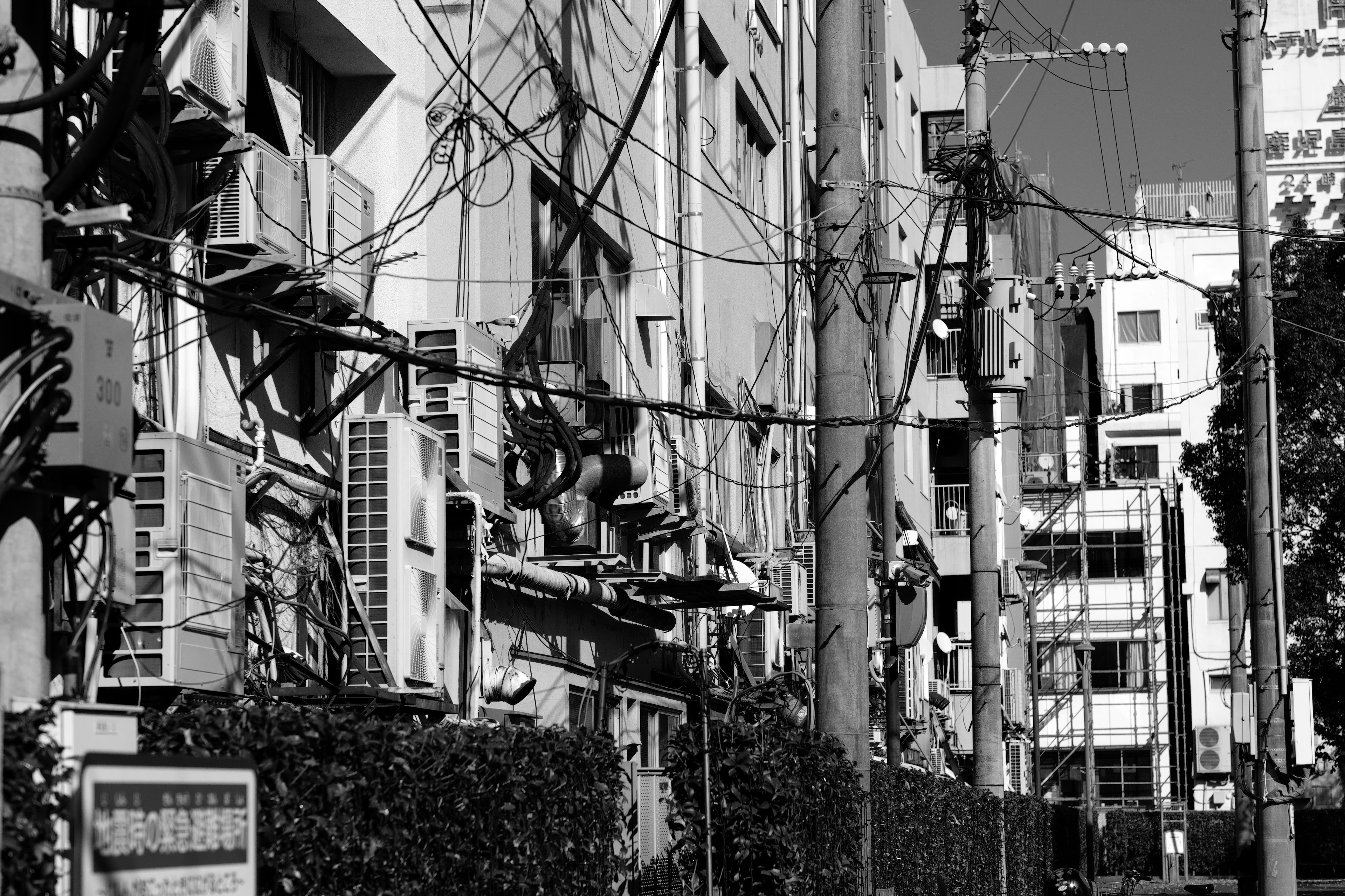 Black and white urban scene featuring buildings with air conditioning units and power lines