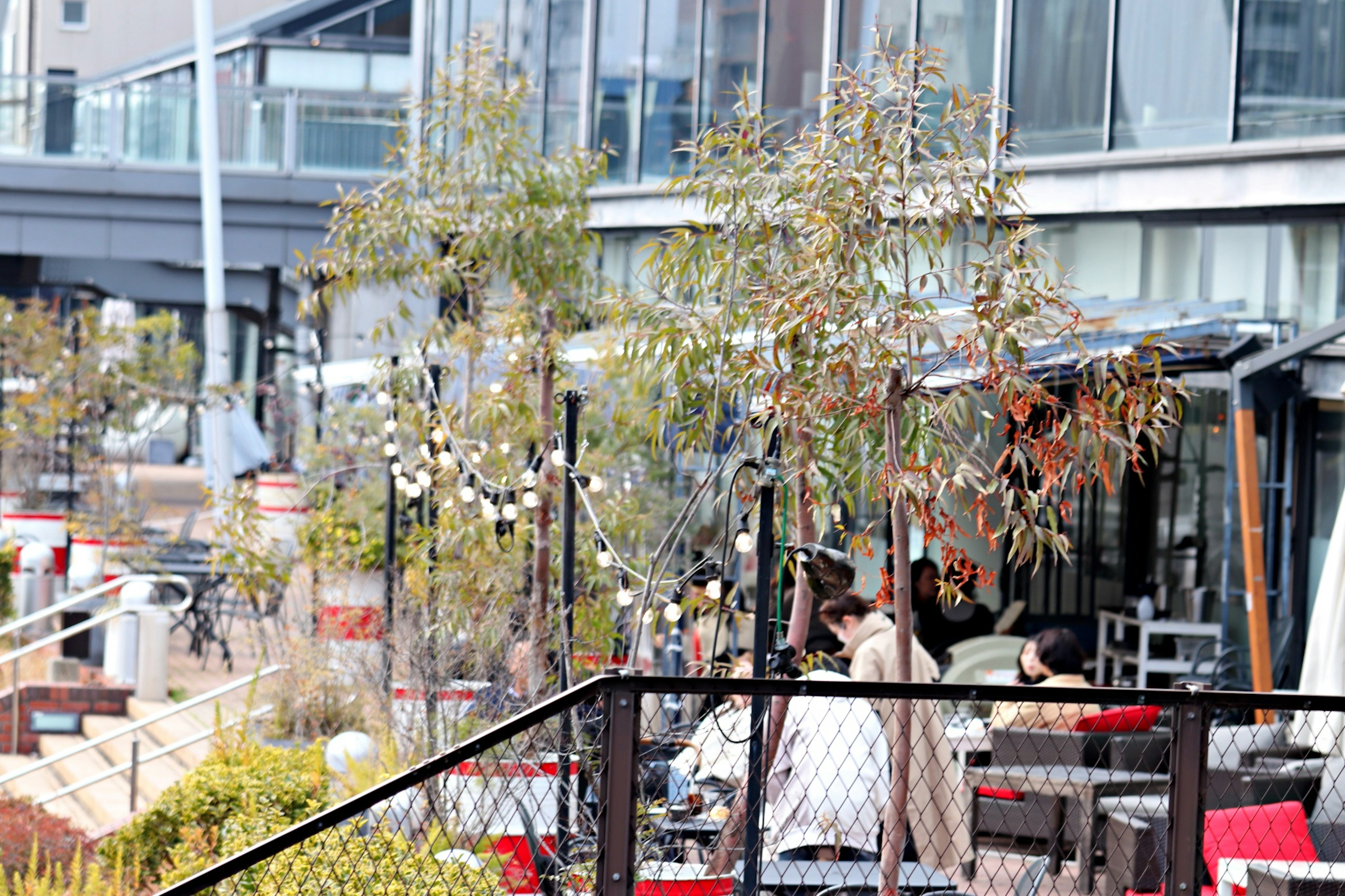 カフェのテラス席に座っている人々と周囲の植物