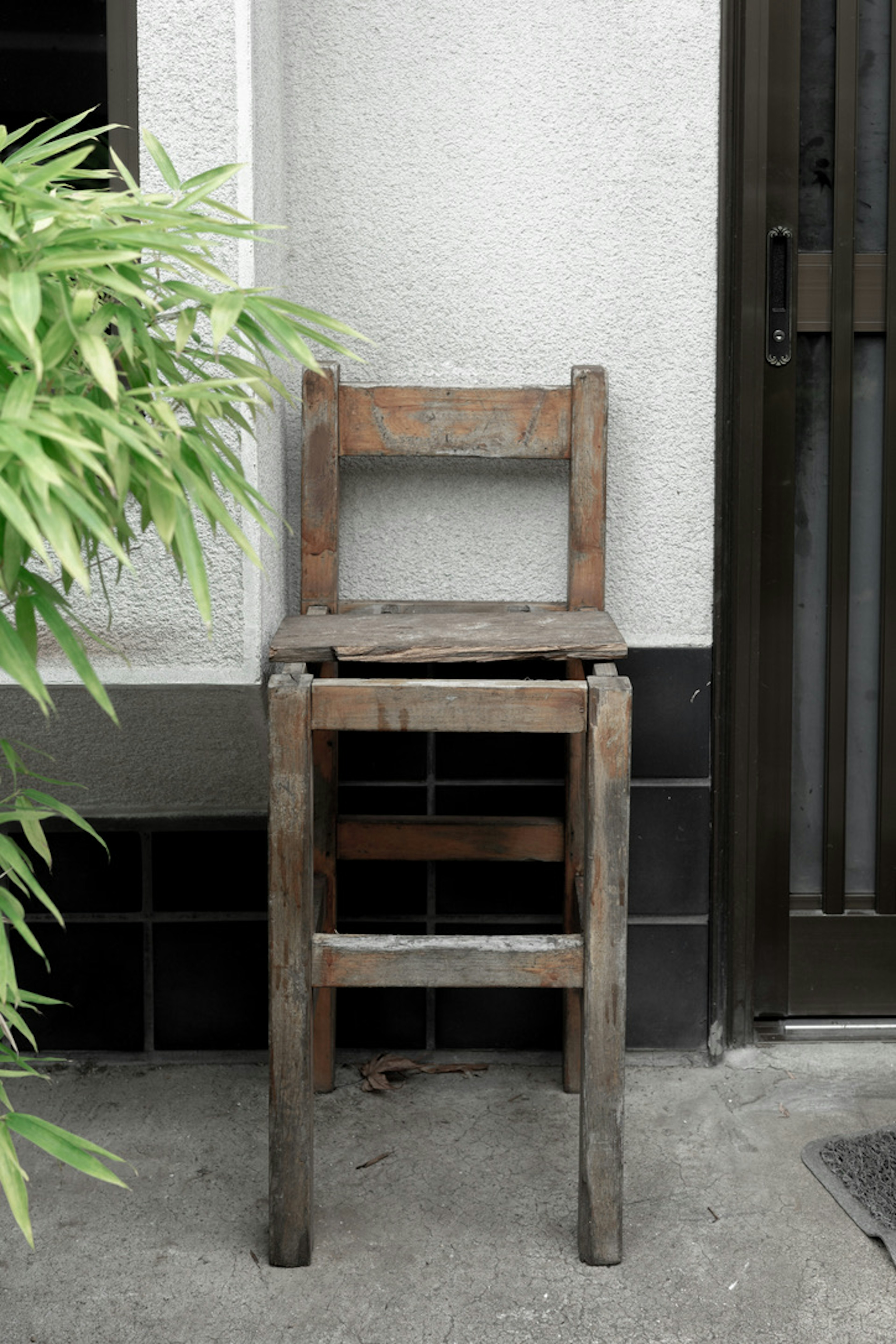 Una silla de madera desgastada colocada junto a una pared