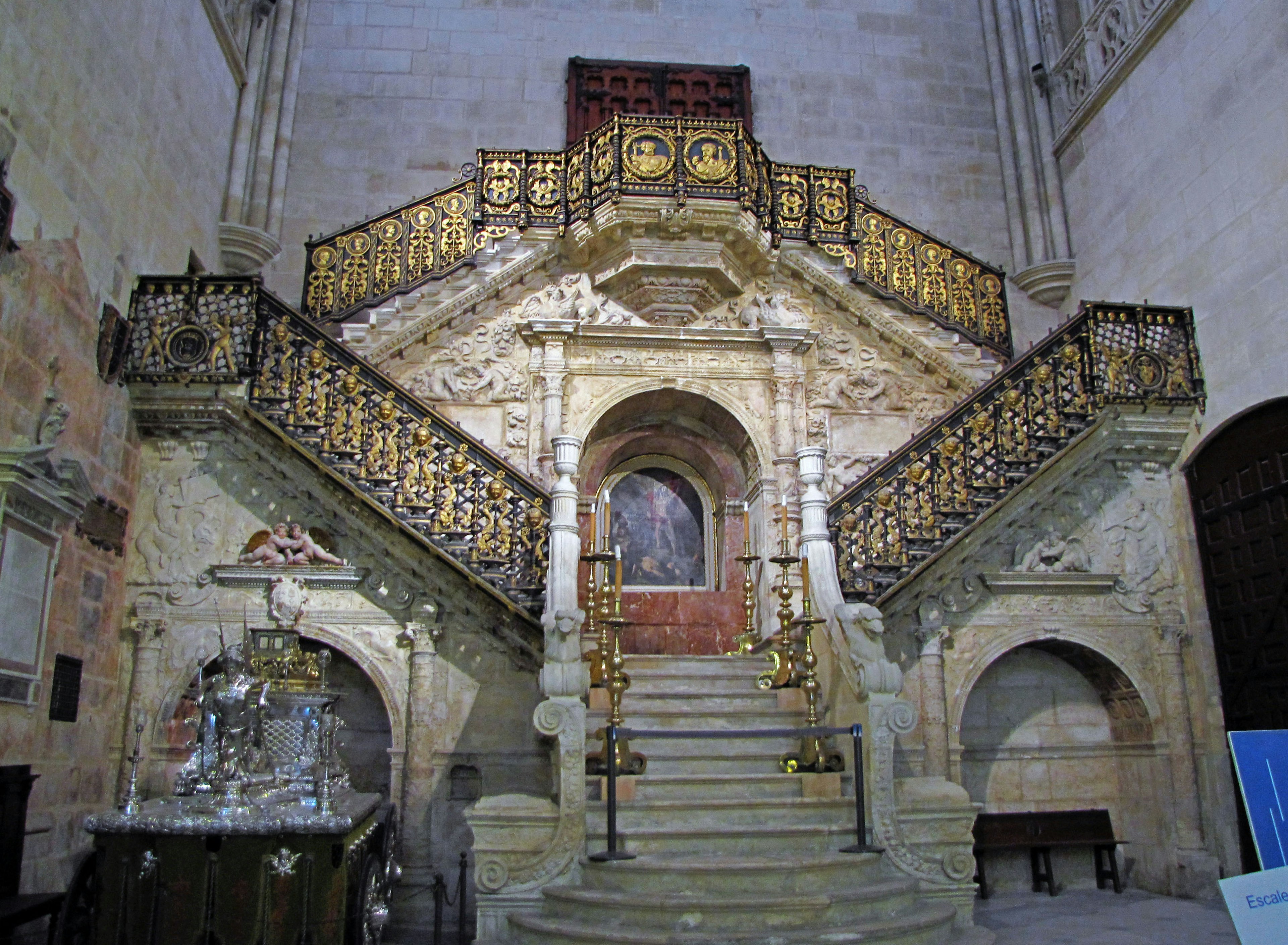 Interior gereja dengan tangga yang dihias dan pegangan tangan emas