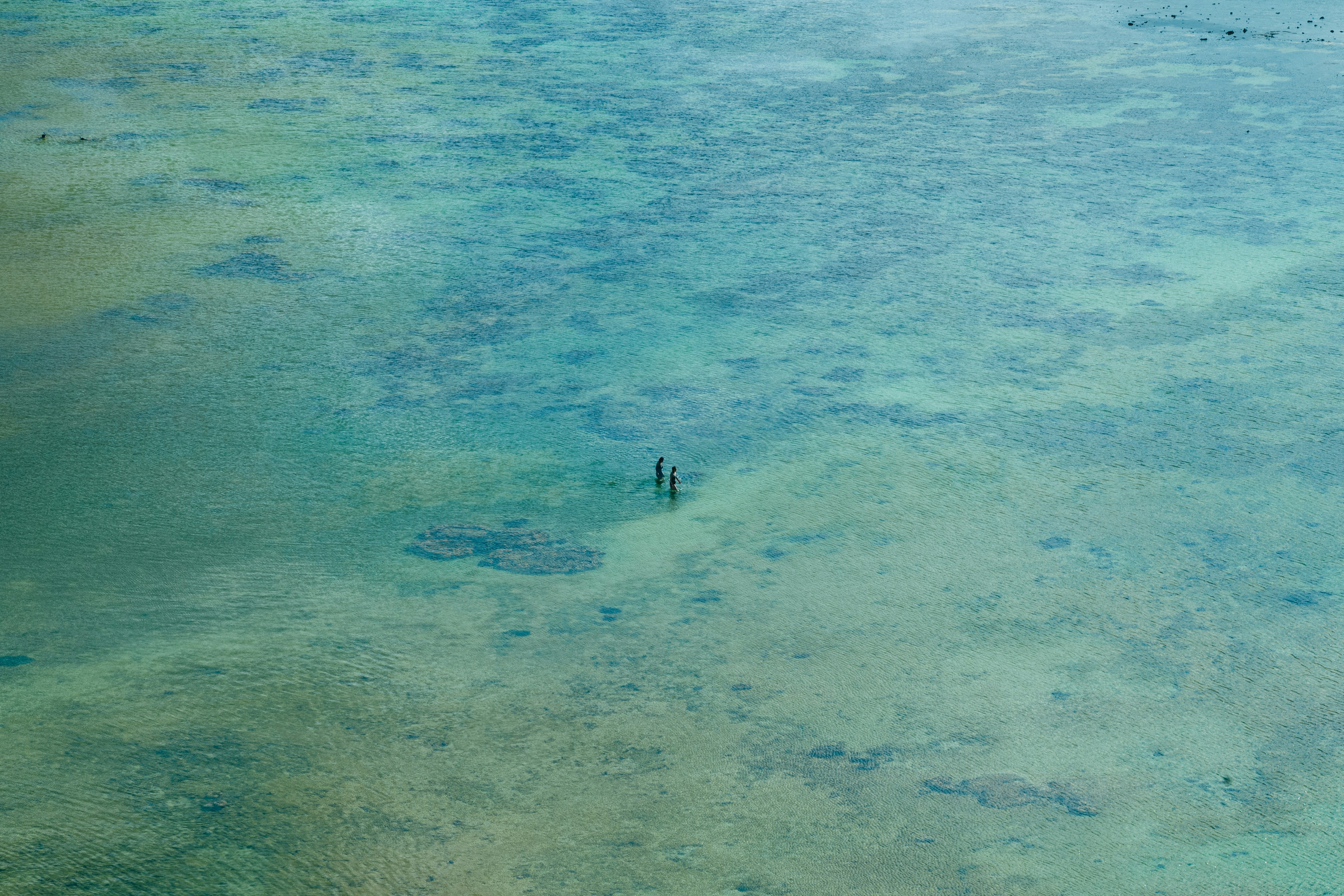 Un petit bateau flottant dans une eau bleue claire avec des récifs coralliens visibles en dessous