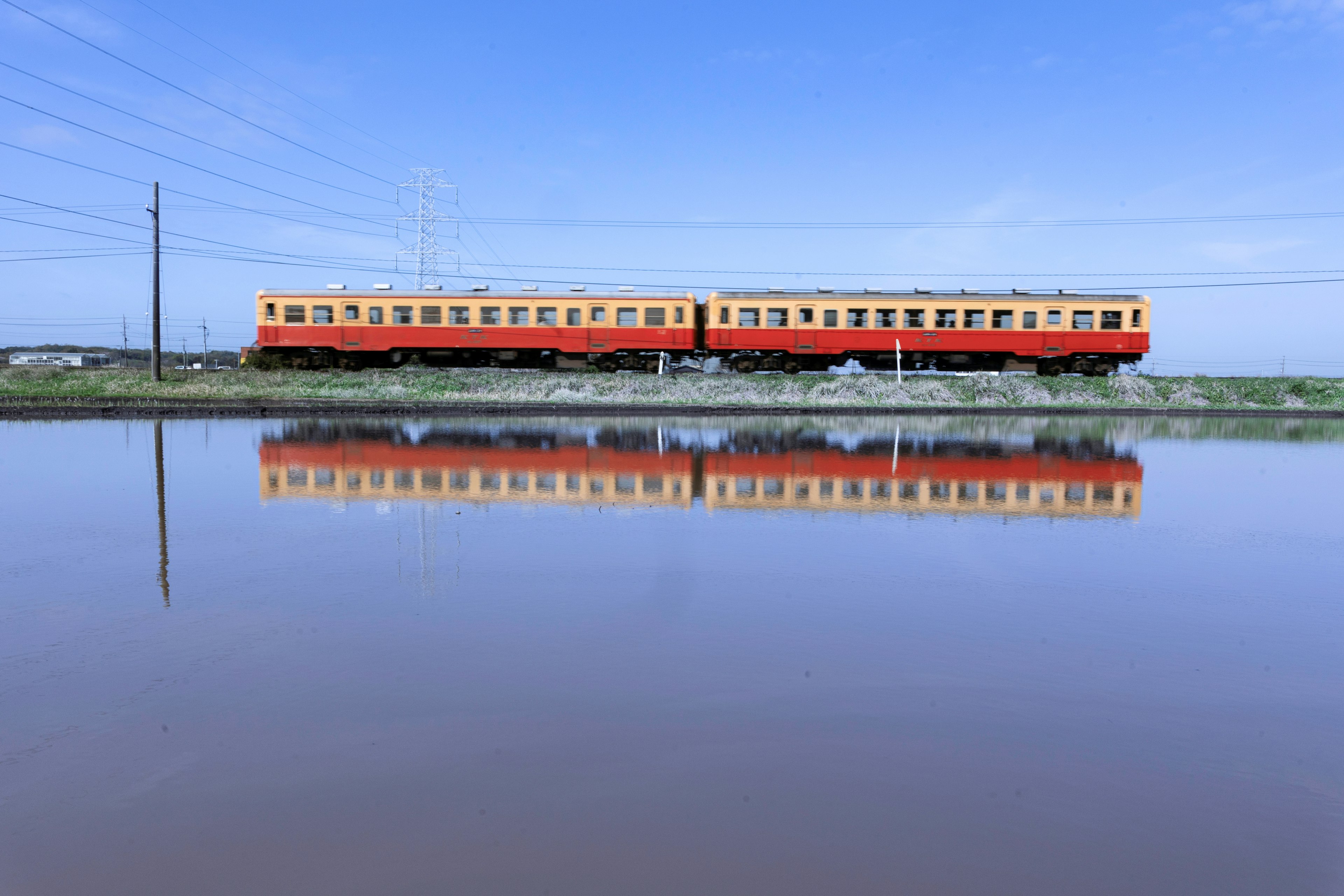 水面に映るオレンジ色の列車と青空