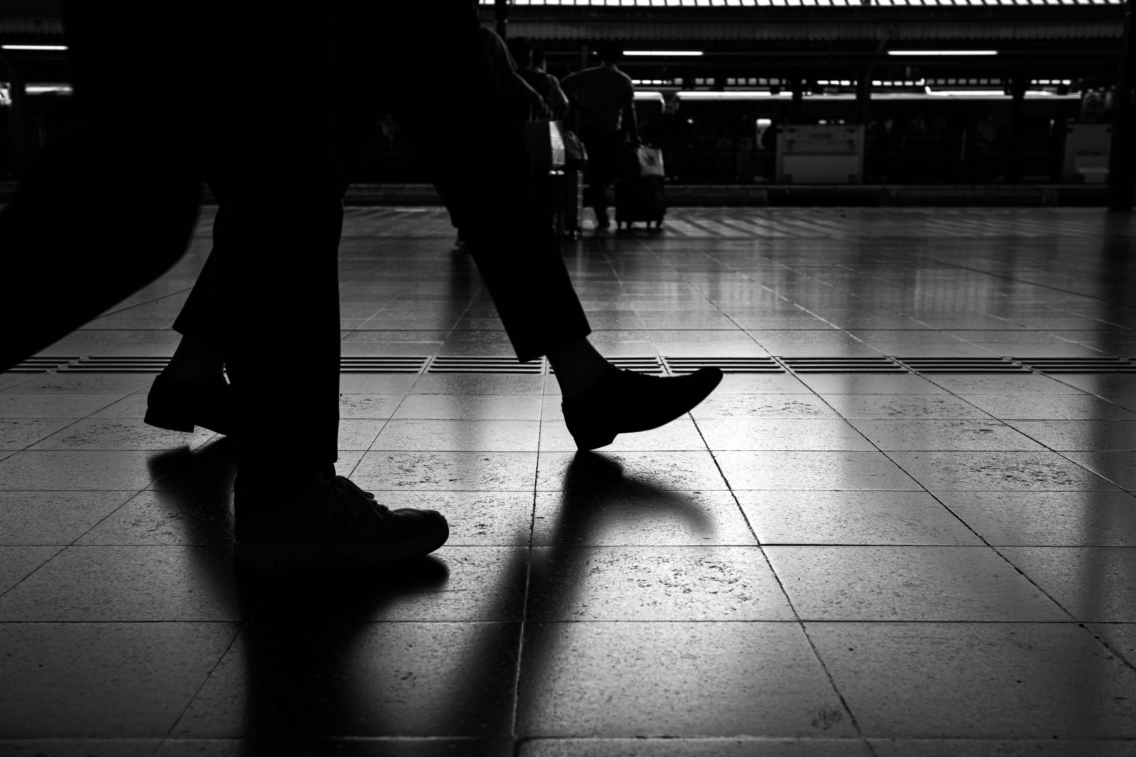 Persone che camminano in una stazione con contrasto di luce e ombra