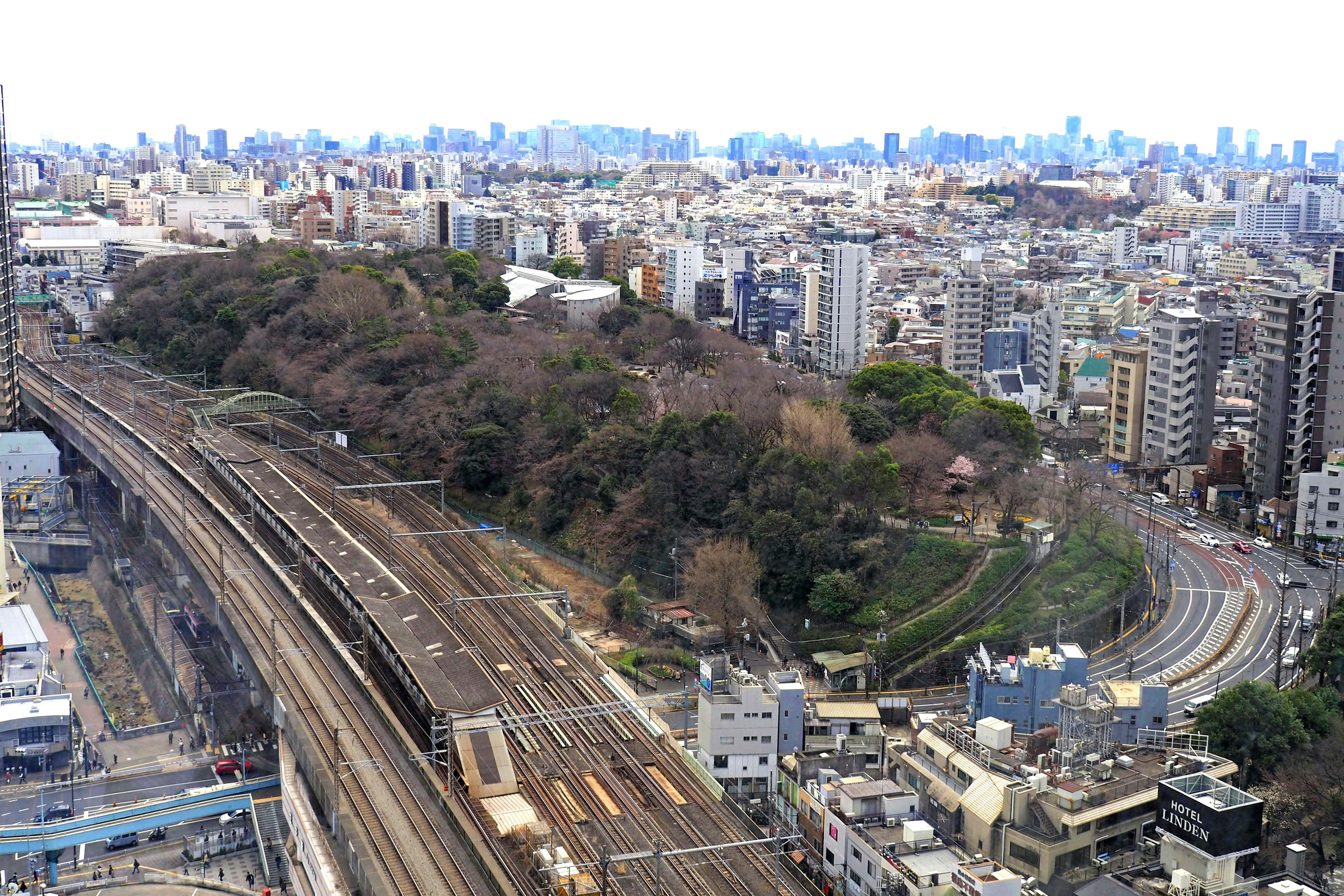 Aerial view of a cityscape featuring railway tracks and green hills