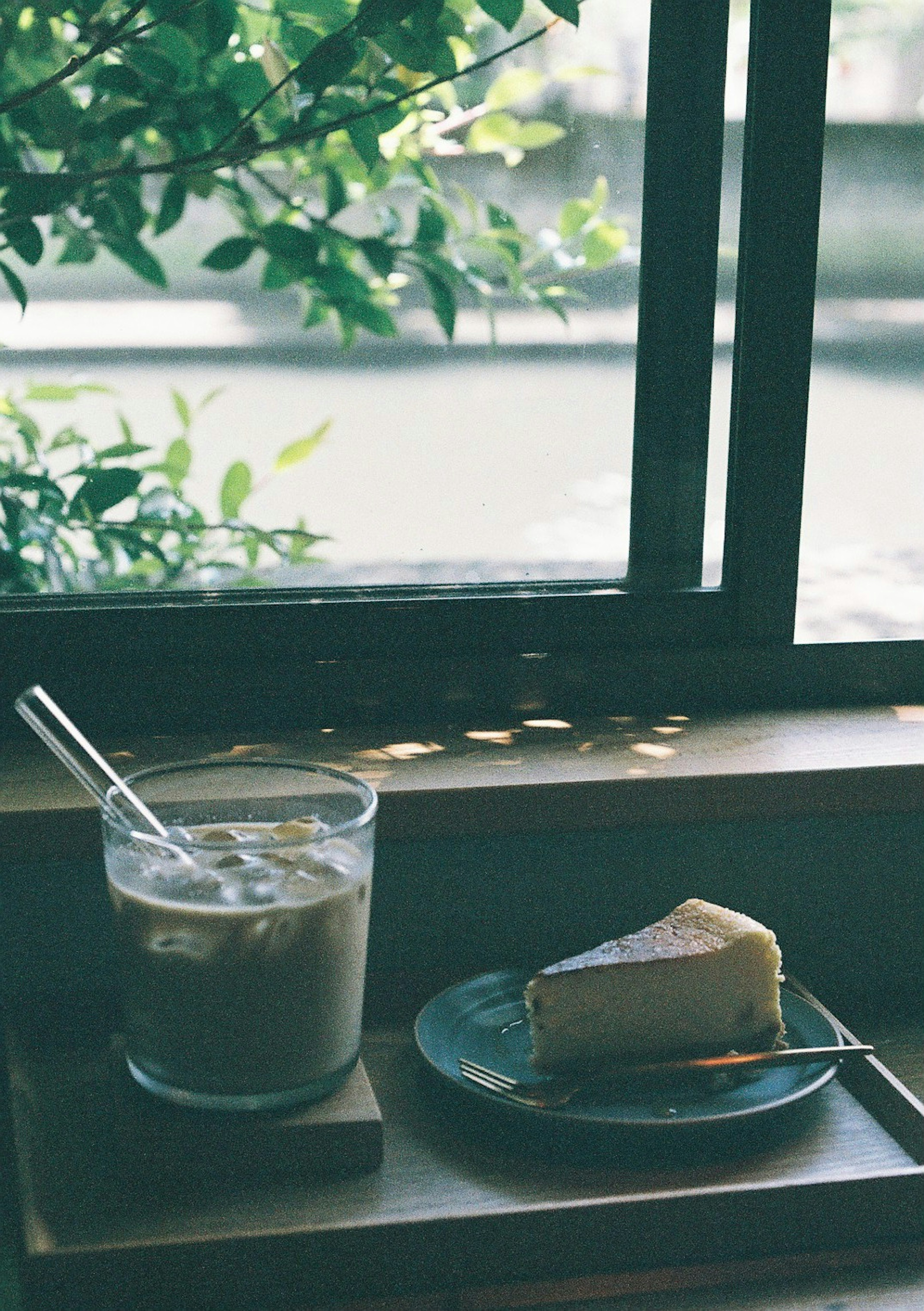 Café helado y cheesecake en un plato junto a la ventana