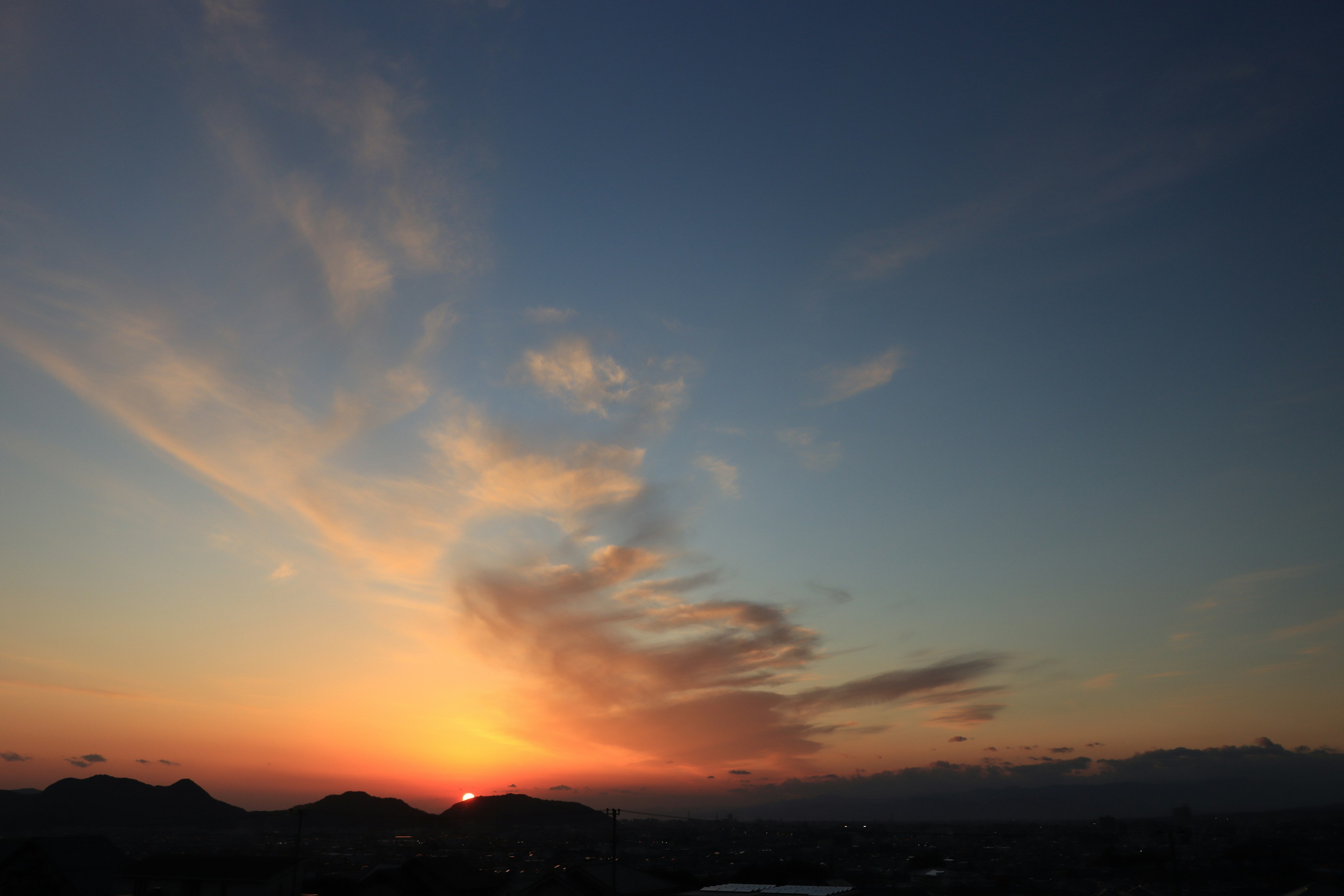 美しい夕焼けが広がり、空にはカラフルな雲が描かれている