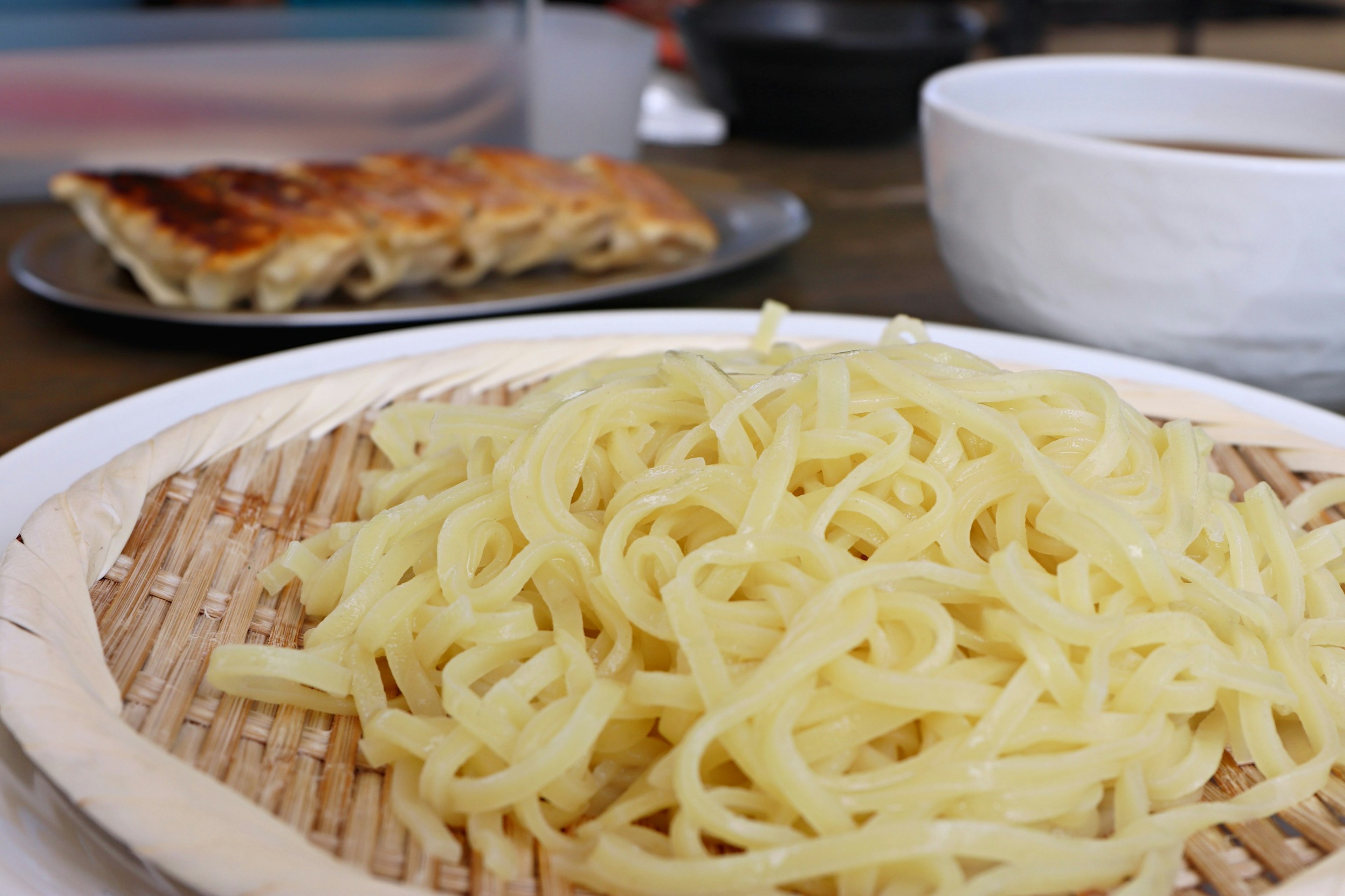 Piring pasta panjang dengan pangsit panggang di latar belakang