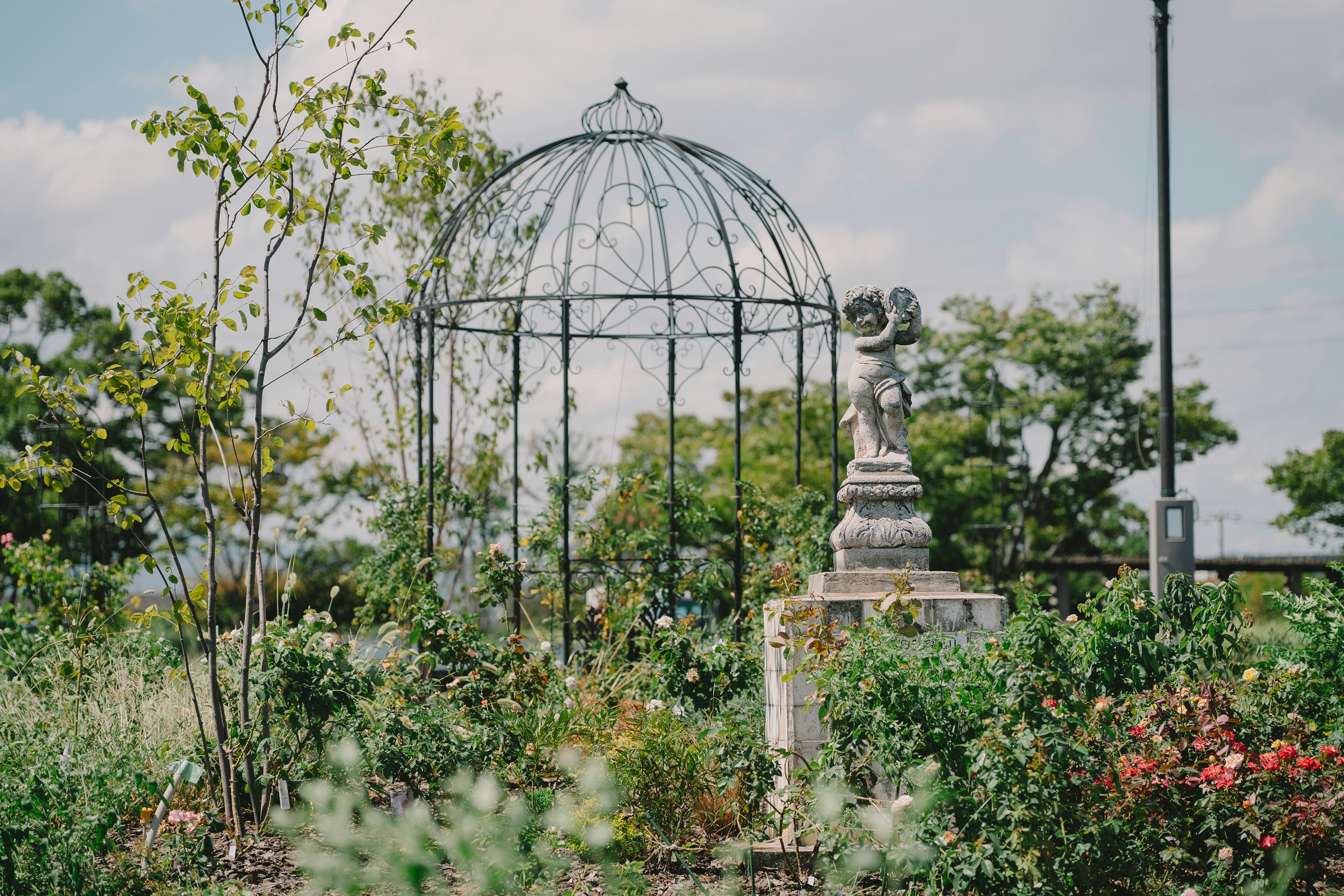 Un beau jardin avec une structure en fer forgé en forme de dôme et une statue sculptée