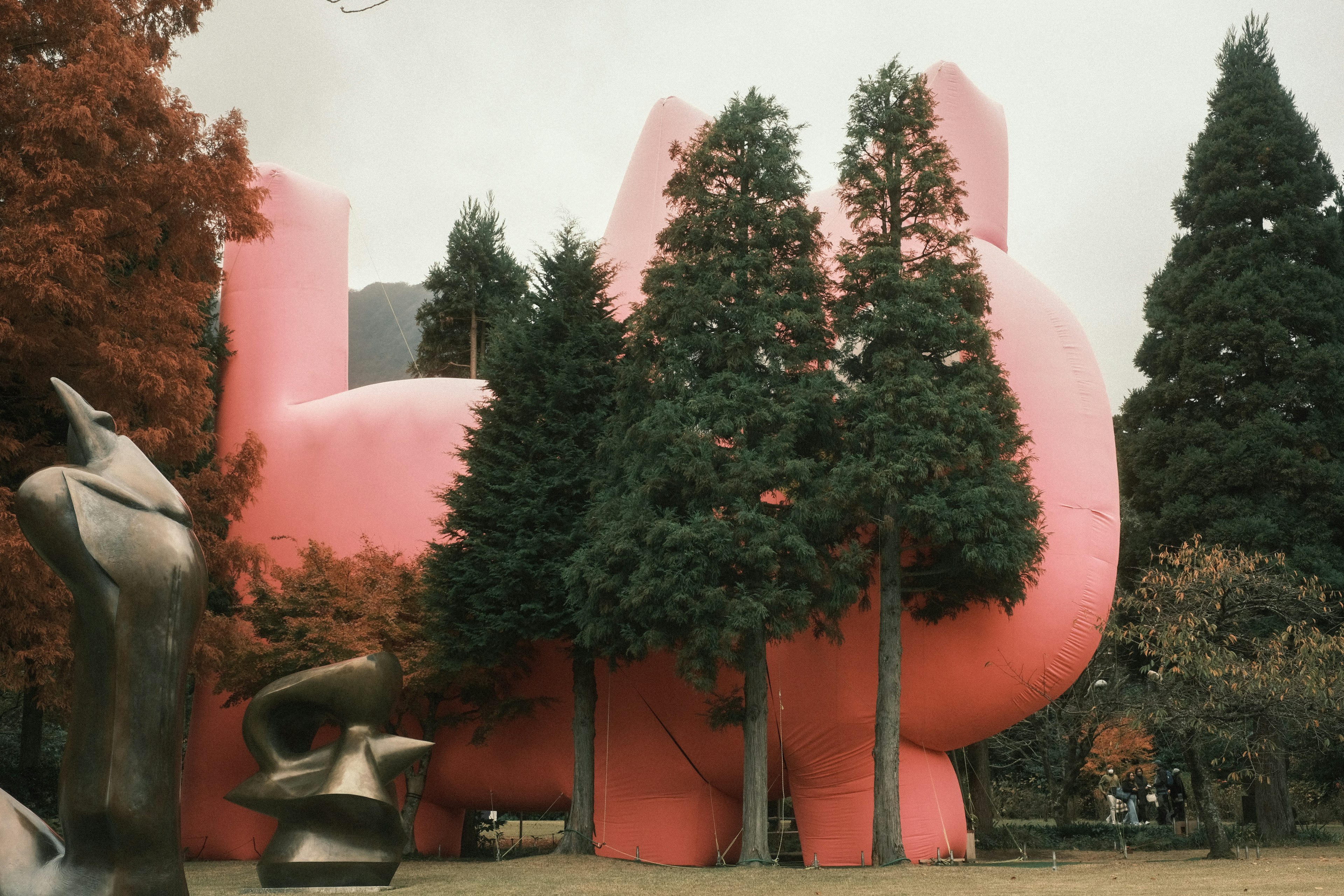 Grande sculpture rose entourée d'arbres verts