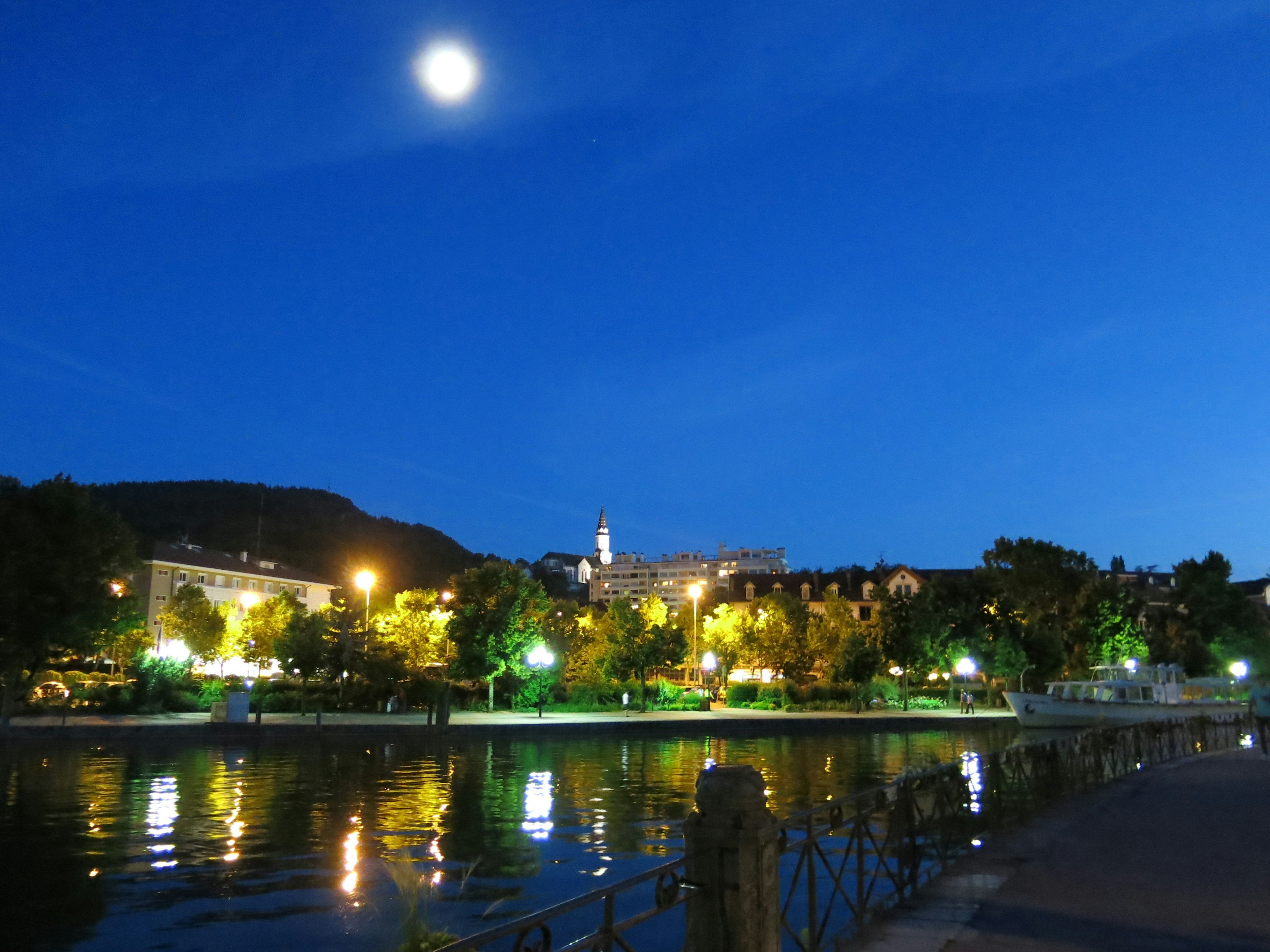 Paesaggio urbano che si riflette sull'acqua con la luna brillante nel cielo notturno