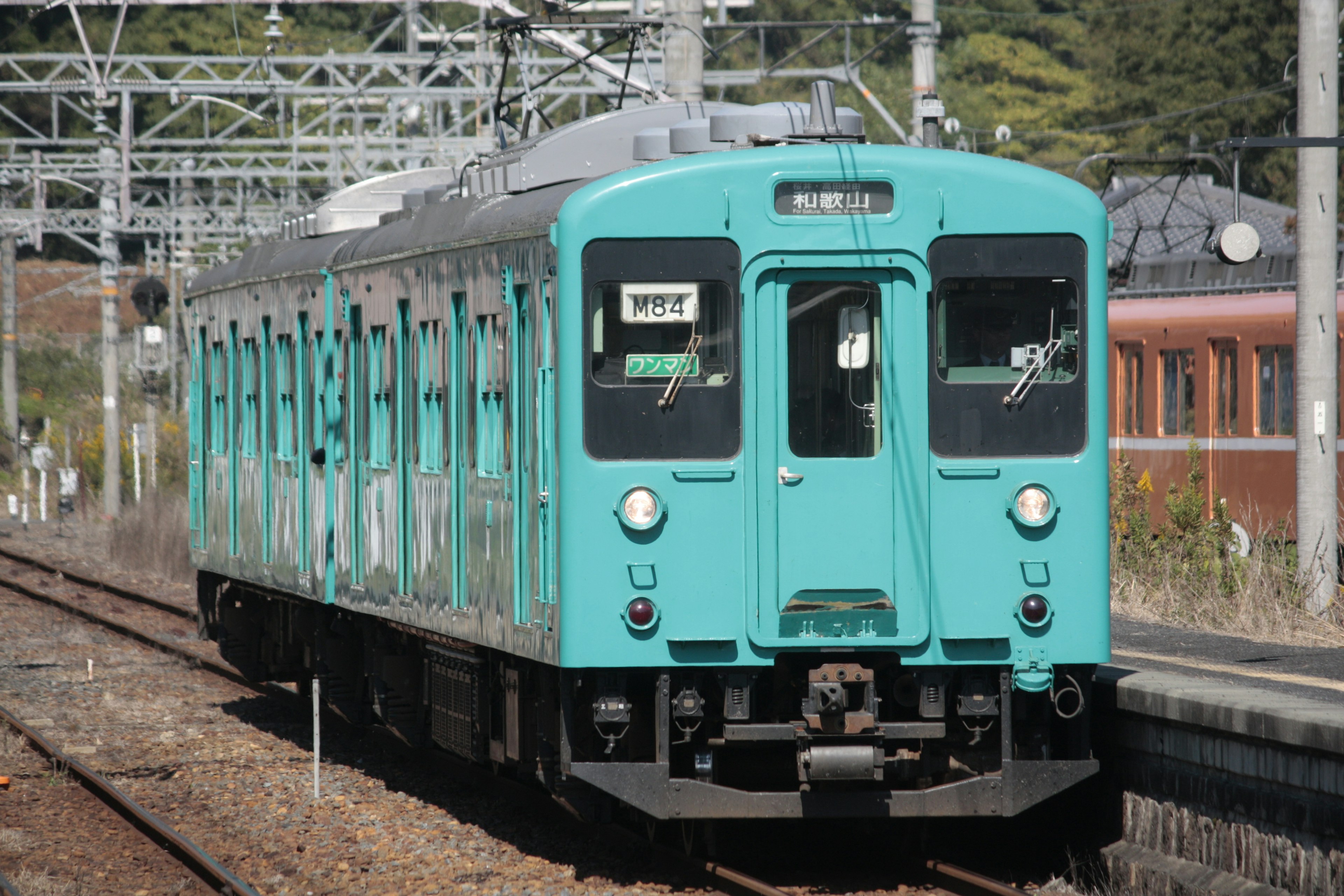 Un treno teal fermo a una stazione