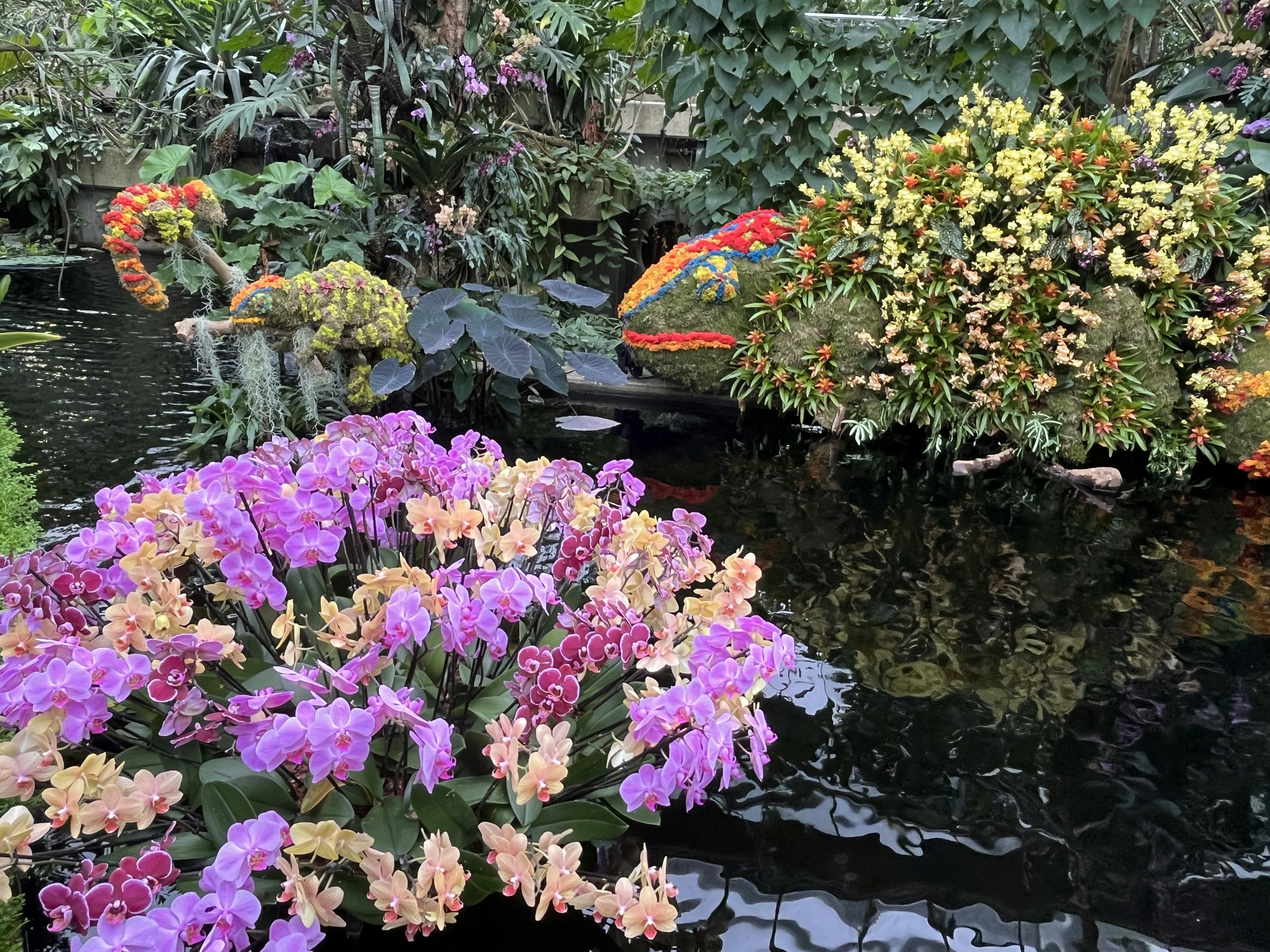 色とりどりの花々と緑に囲まれた池の風景