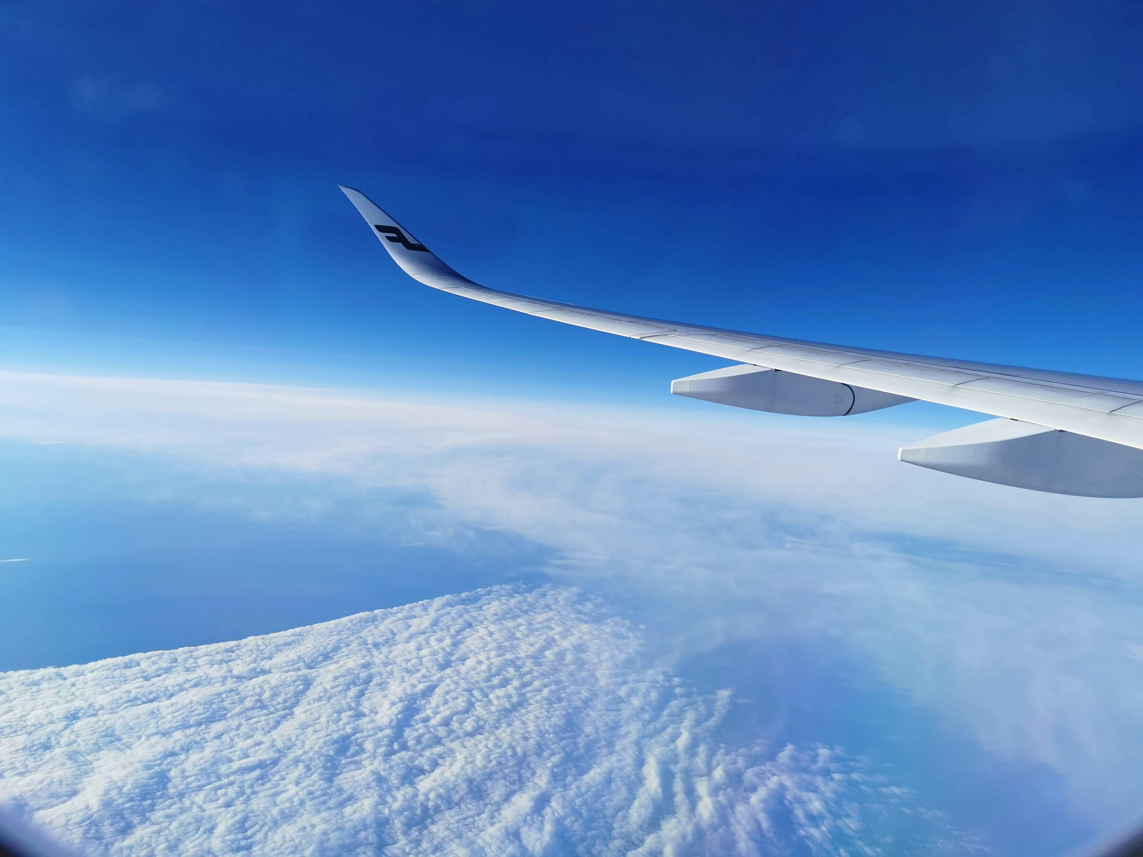 Flugzeugflügel vor blauem Himmel und Wolken