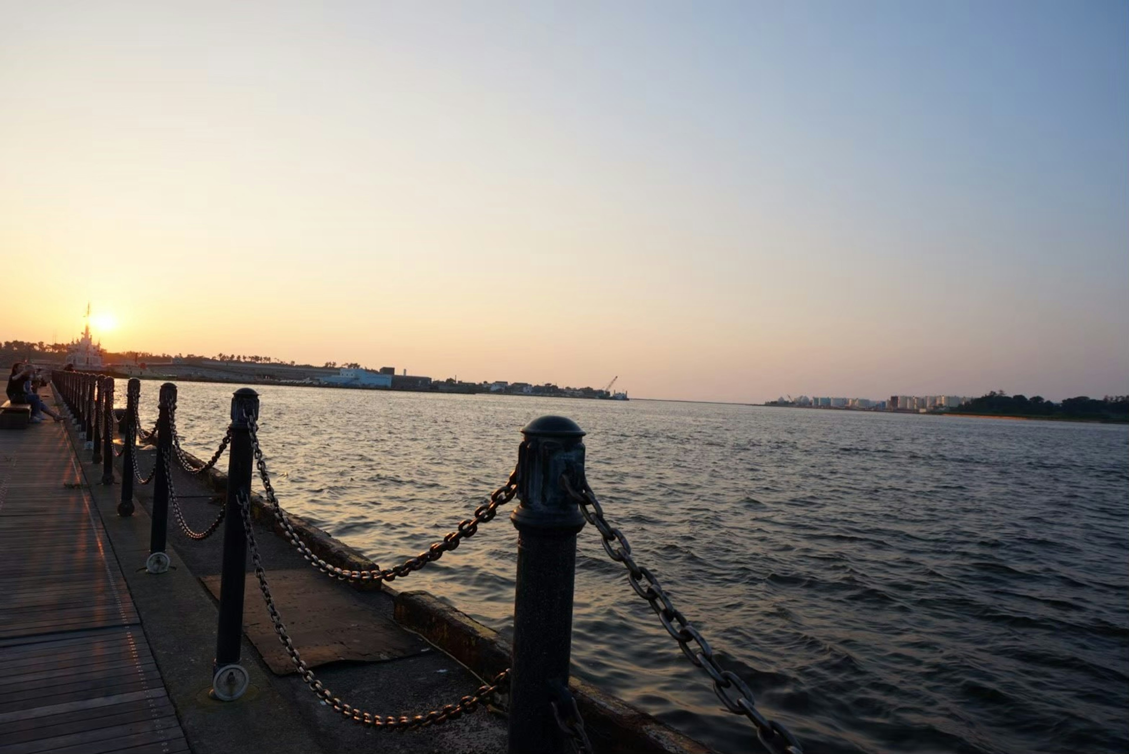 Vue pittoresque d'une rive de rivière au coucher du soleil avec une clôture en chaîne