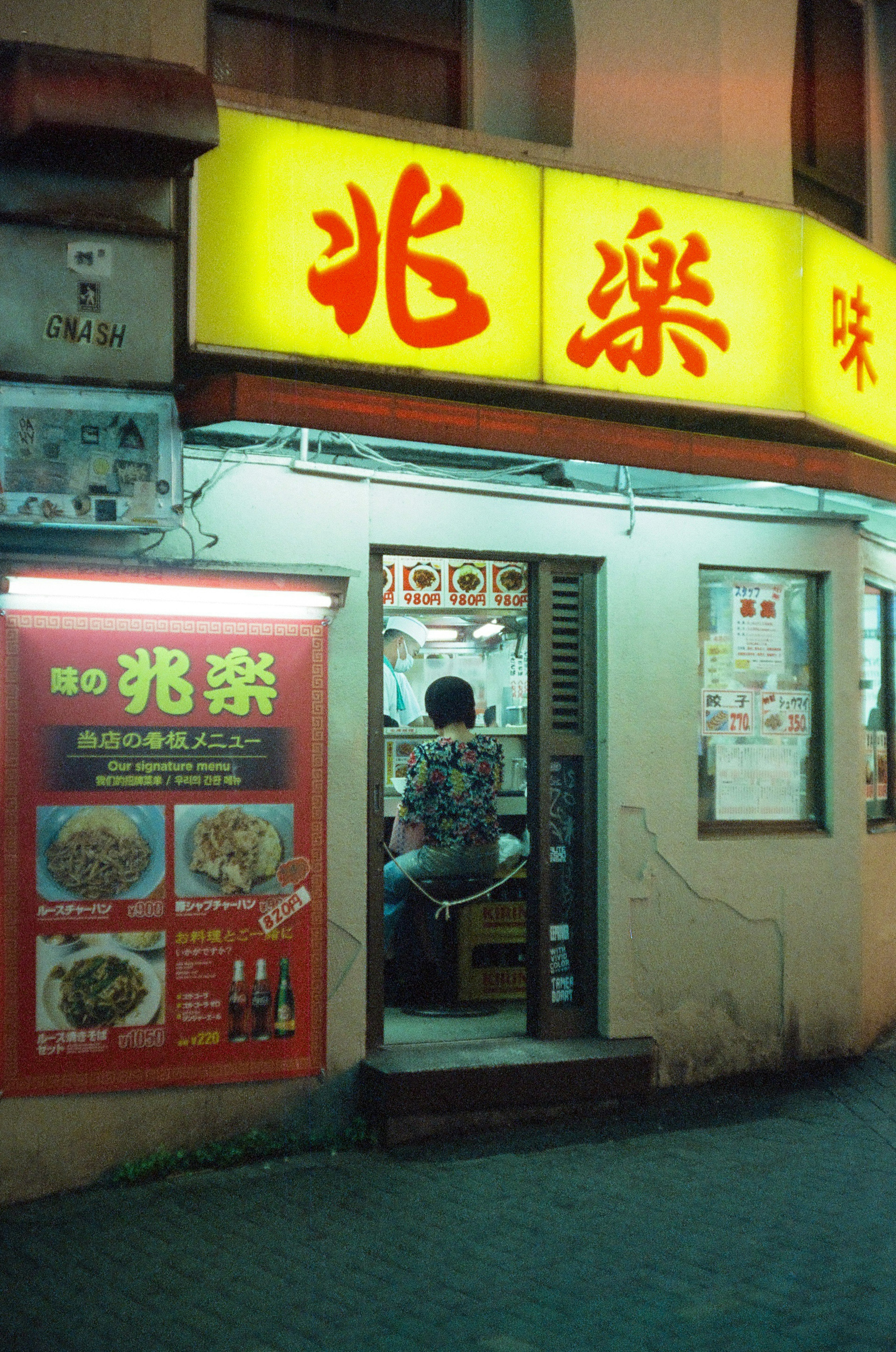 Äußeres eines chinesischen Restaurants in einer dunklen Straße Helles Schild und Menü sichtbar