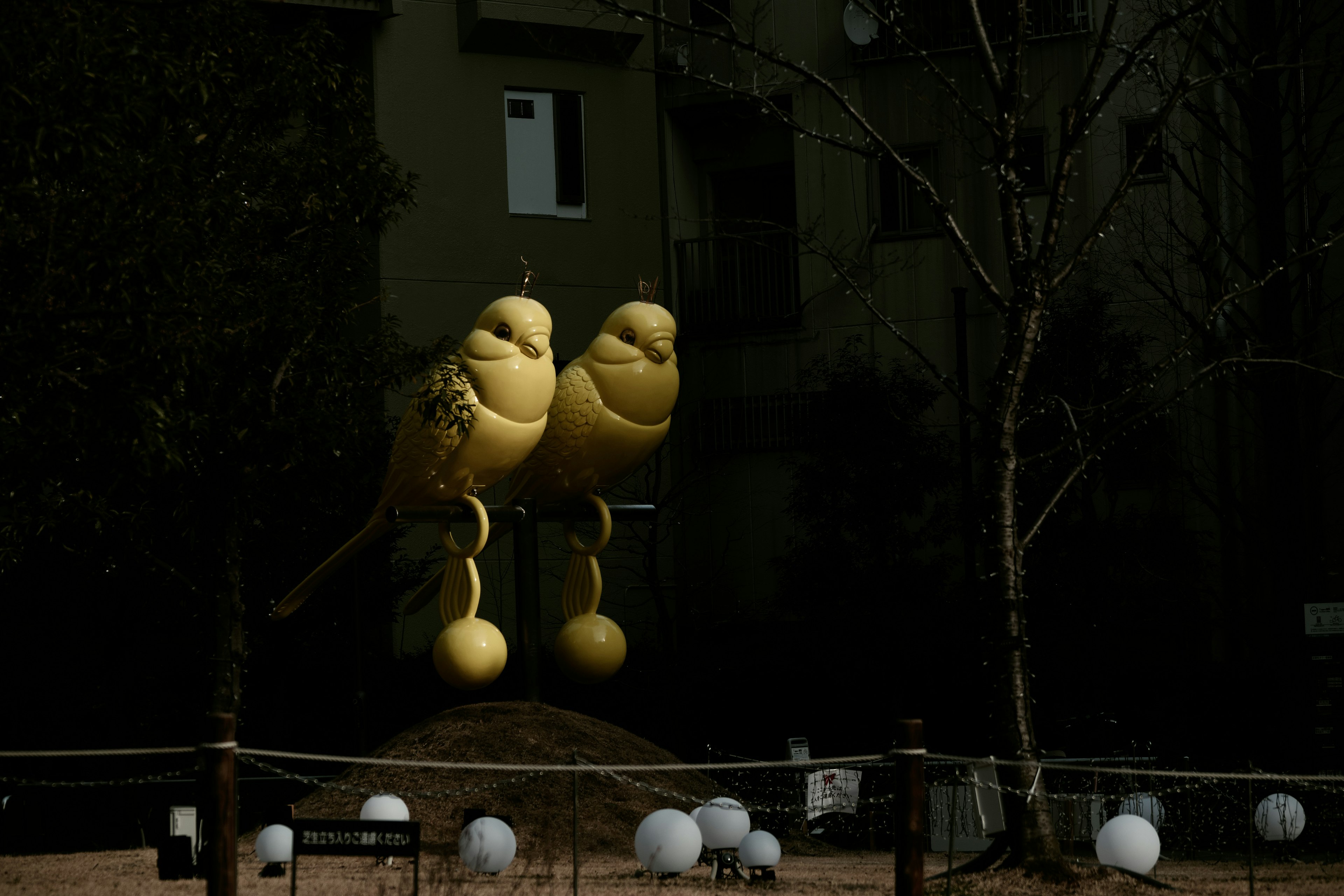 Deux sculptures d'oiseaux jaunes se tenant dans un parc