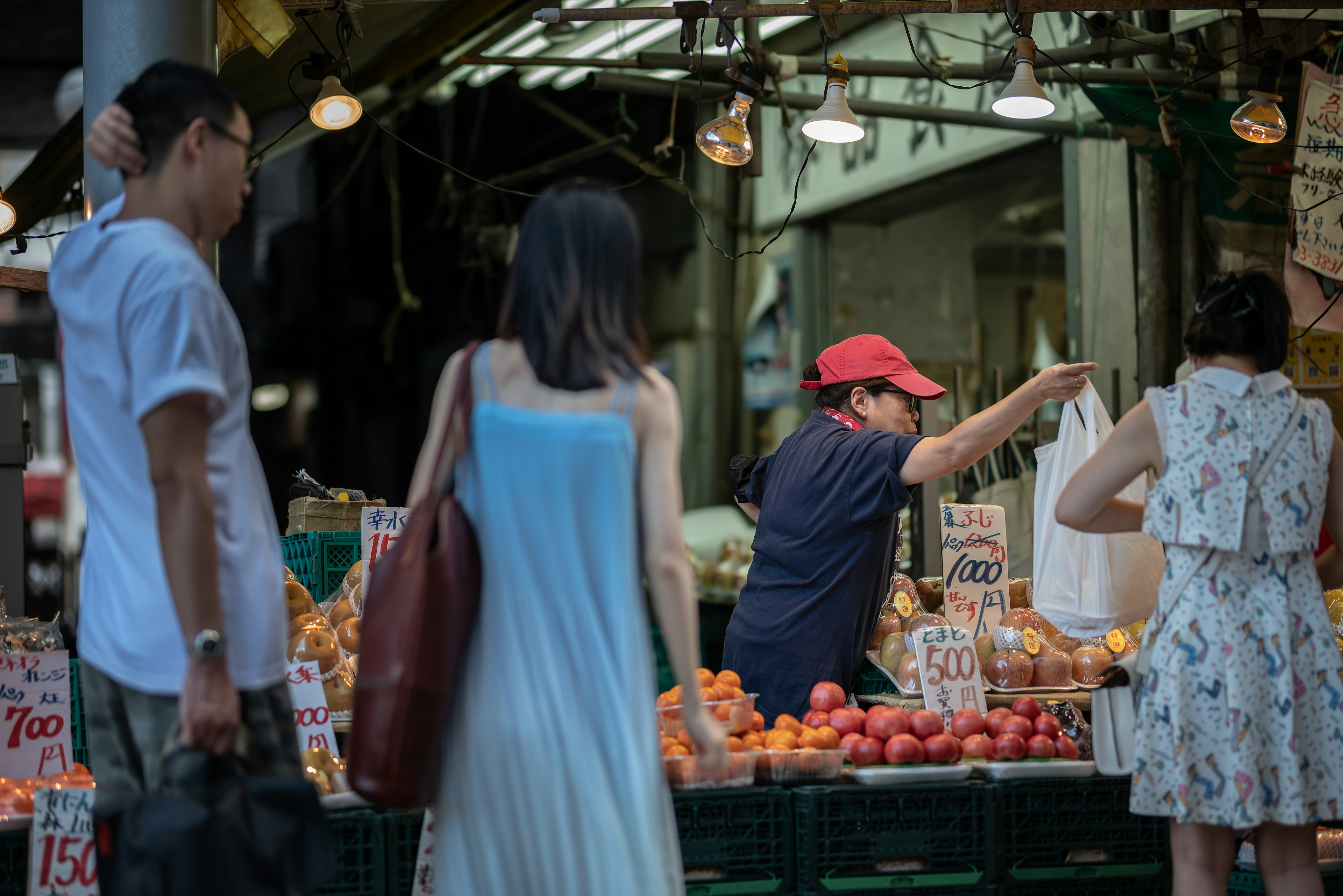 Personas comprando en un puesto de frutas en un mercado