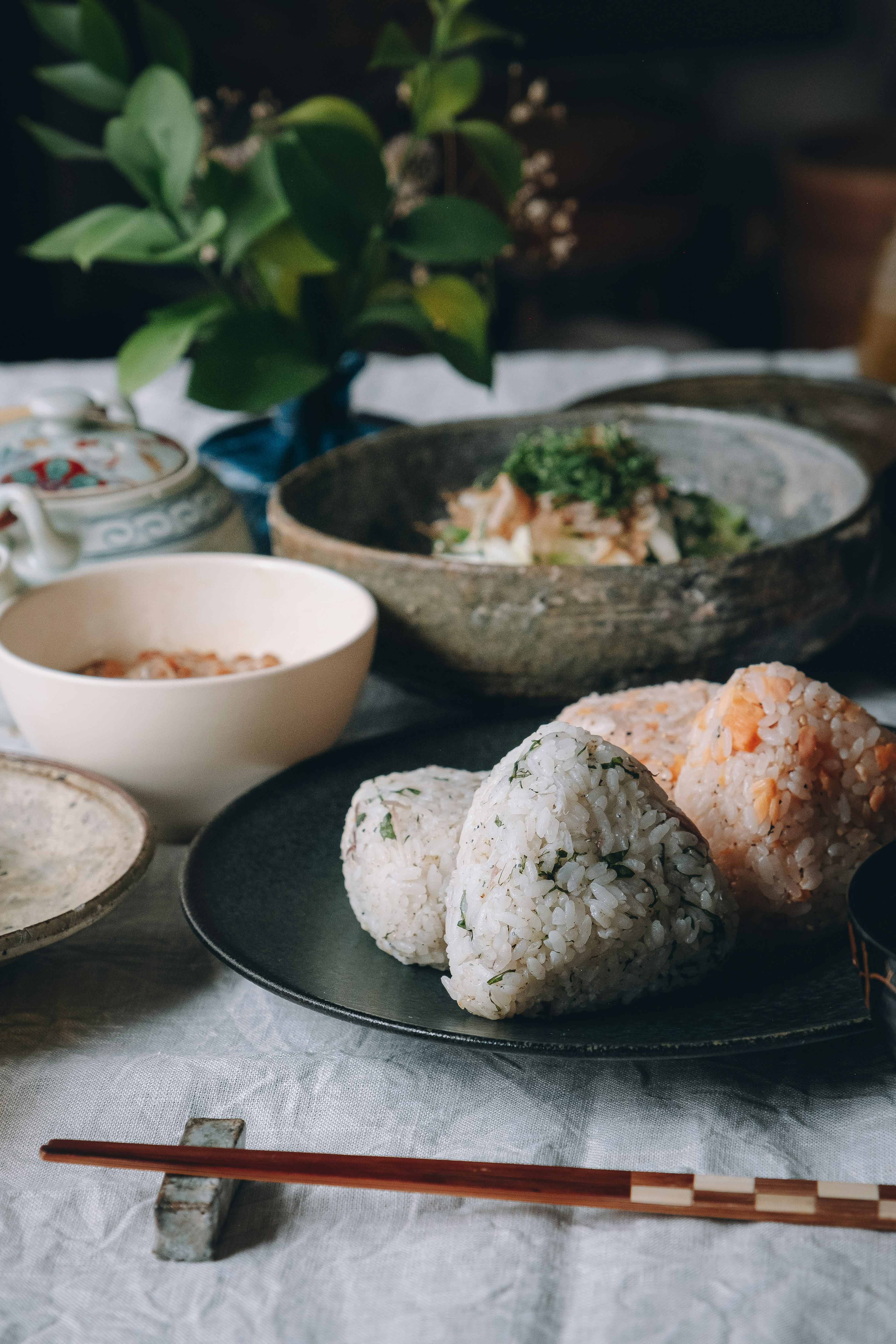 Un plato de onigiri con varios rellenos rodeado de platos japoneses tradicionales