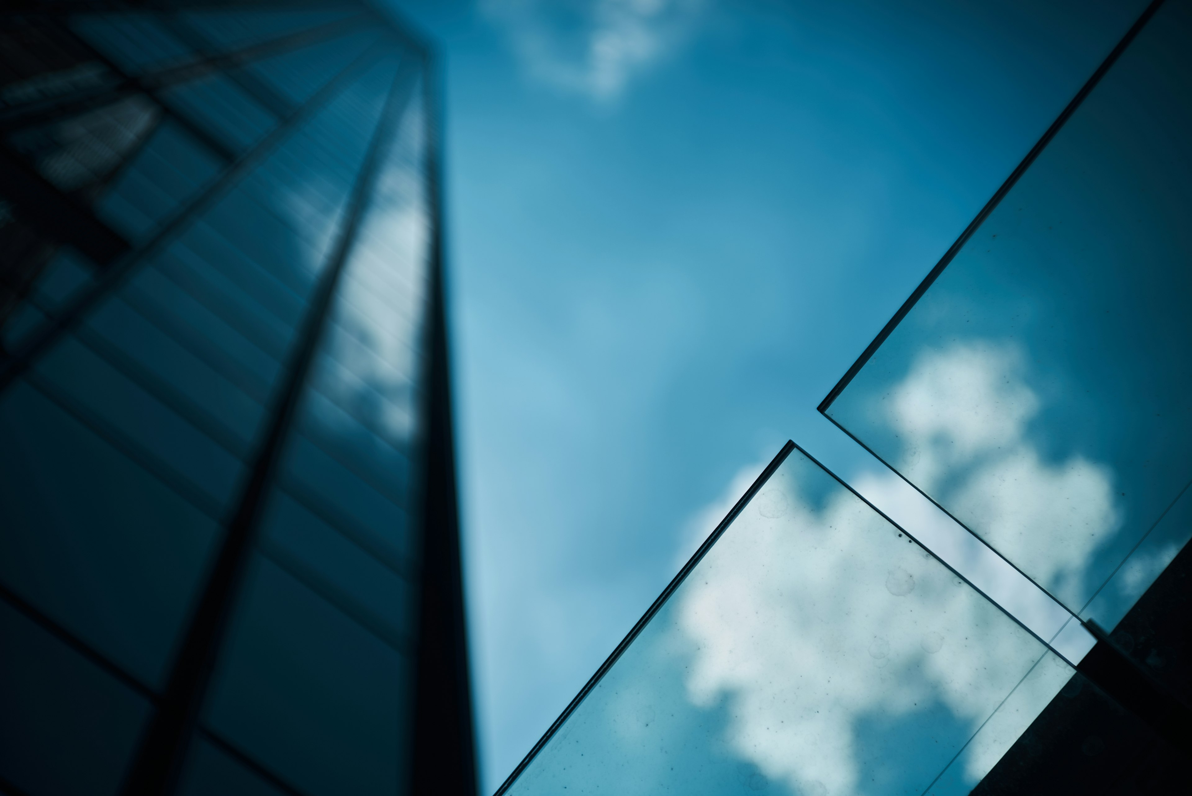 Reflection of blue sky in a skyscraper glass with an upward perspective