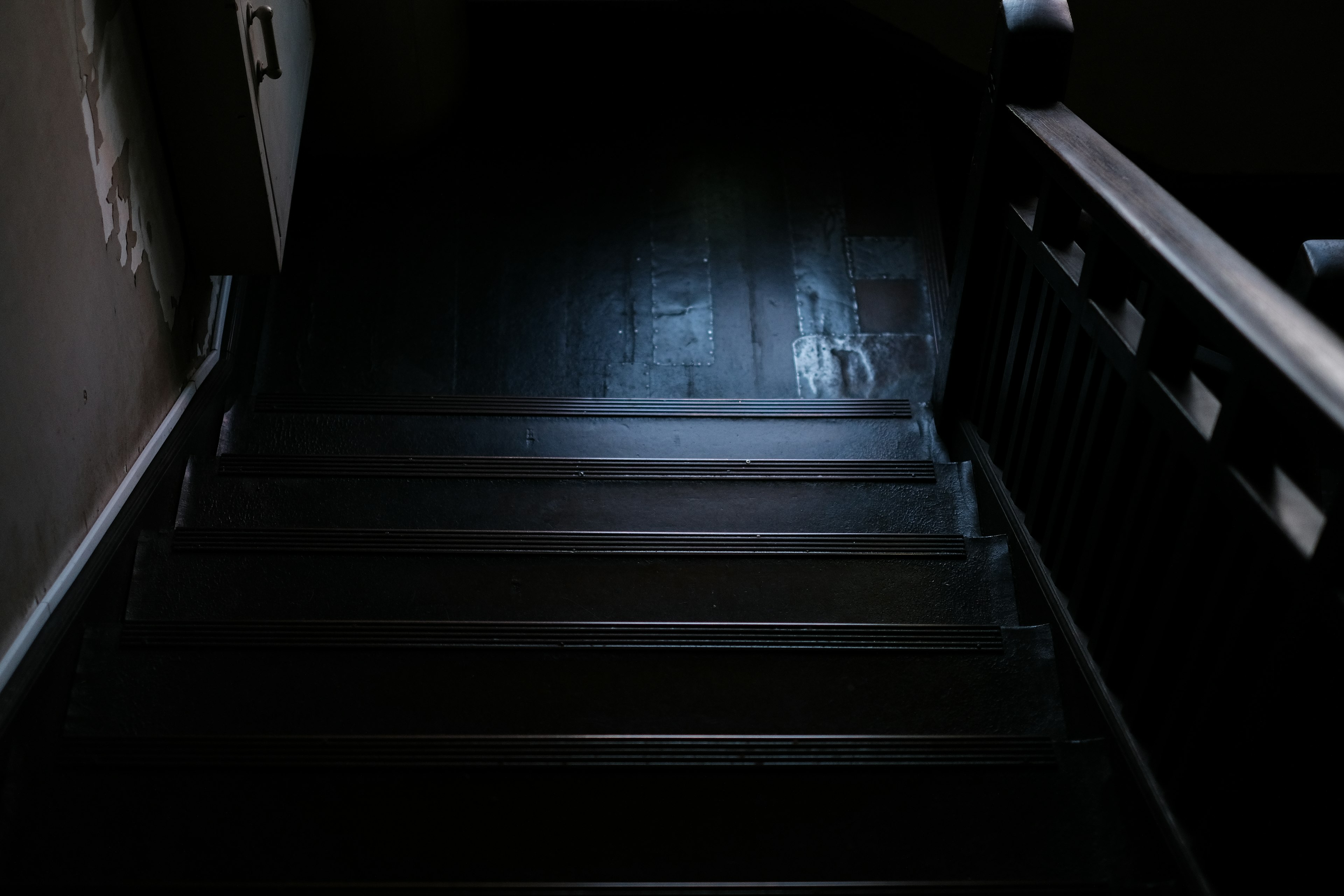 View looking down a dark wooden staircase with a handrail