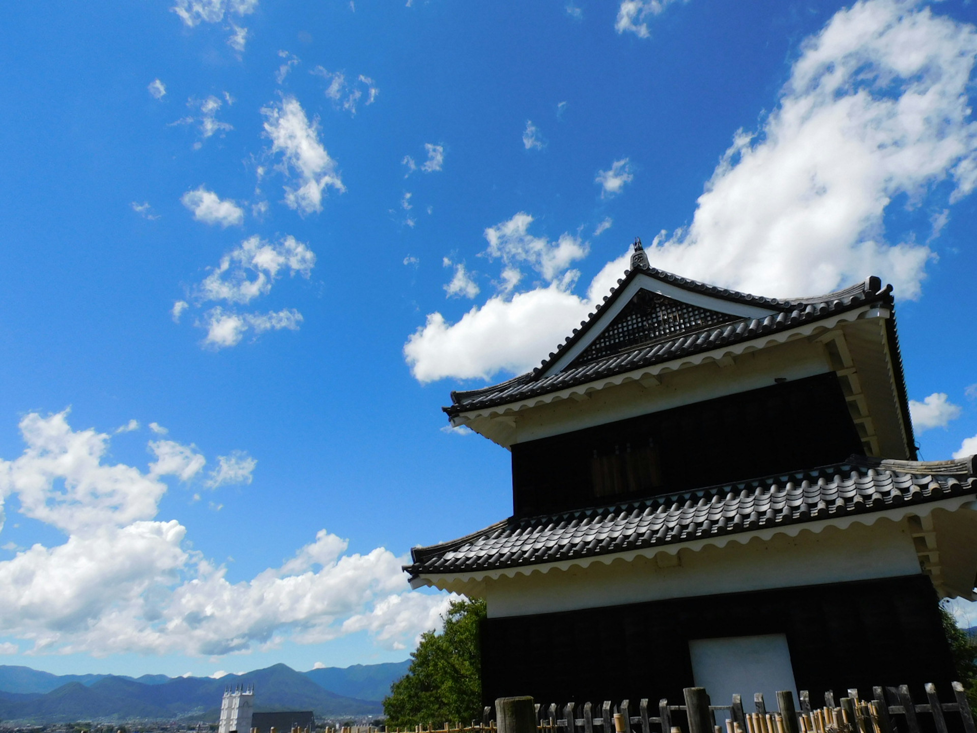 青空の下にある伝統的な日本の城の建物と山々