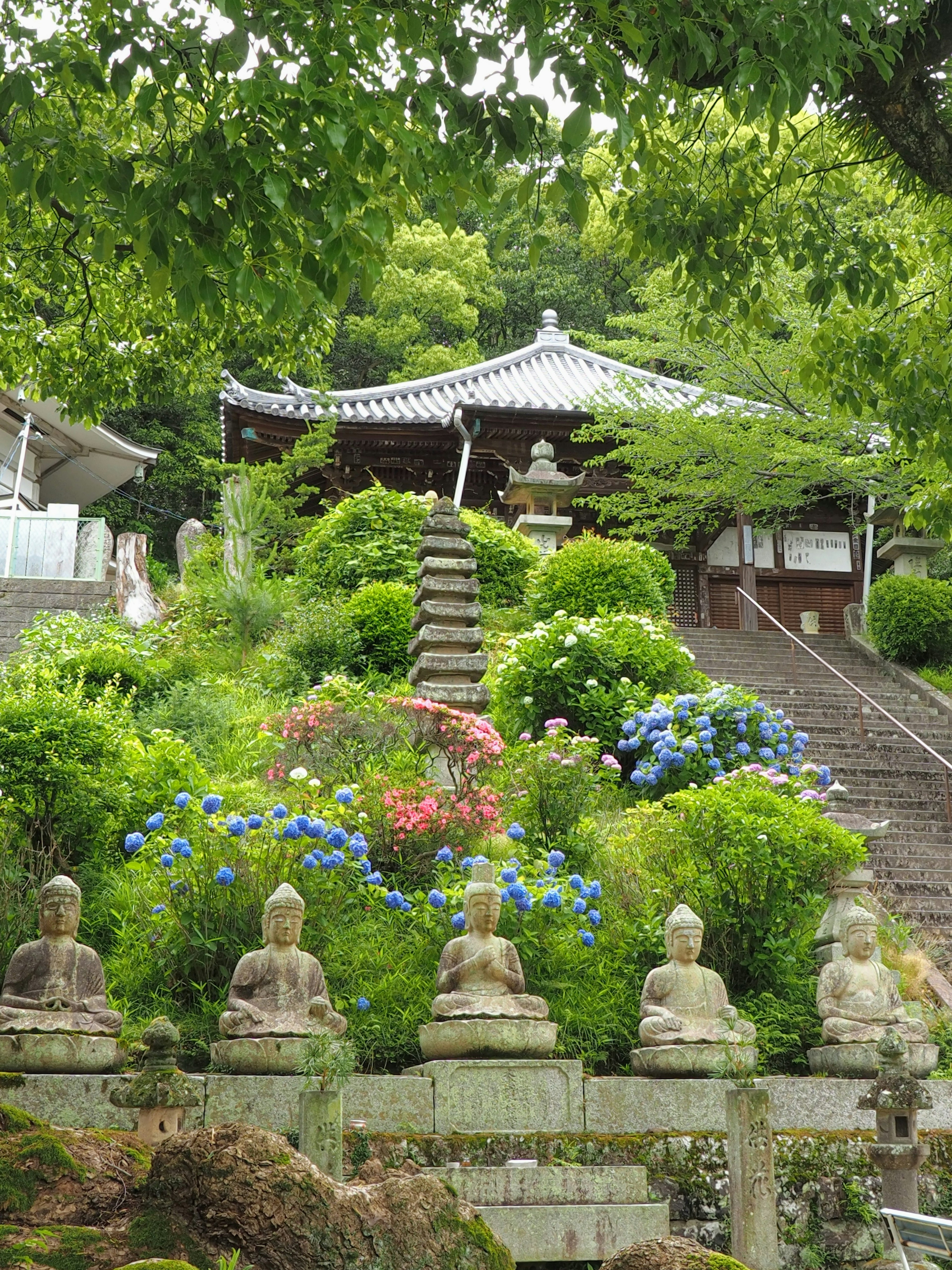 Templo con escaleras rodeadas de follaje verde y estatuas de Buda