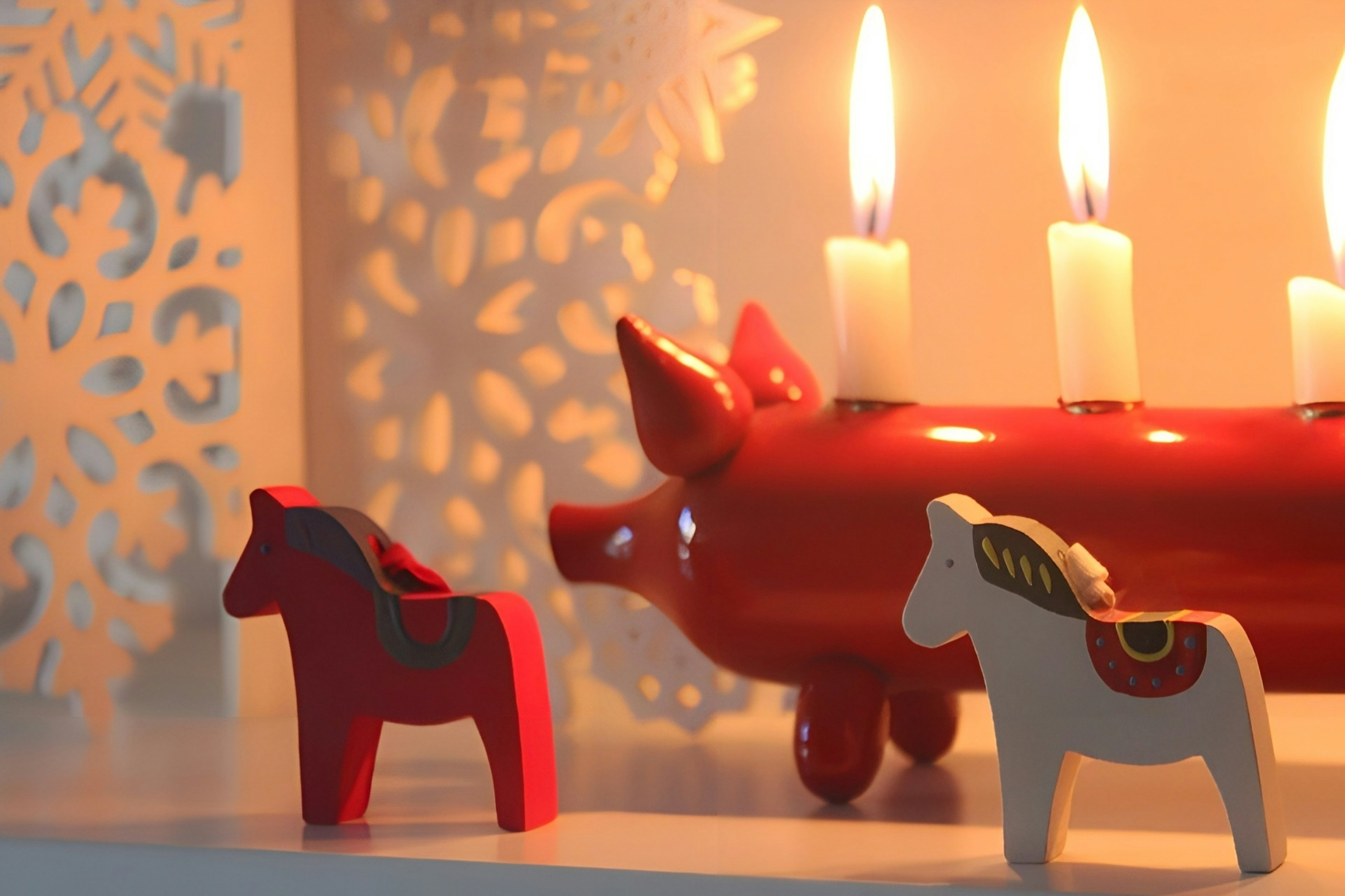 Una escena cálida con un candelabro de cerdo rojo y figuras de caballos de madera