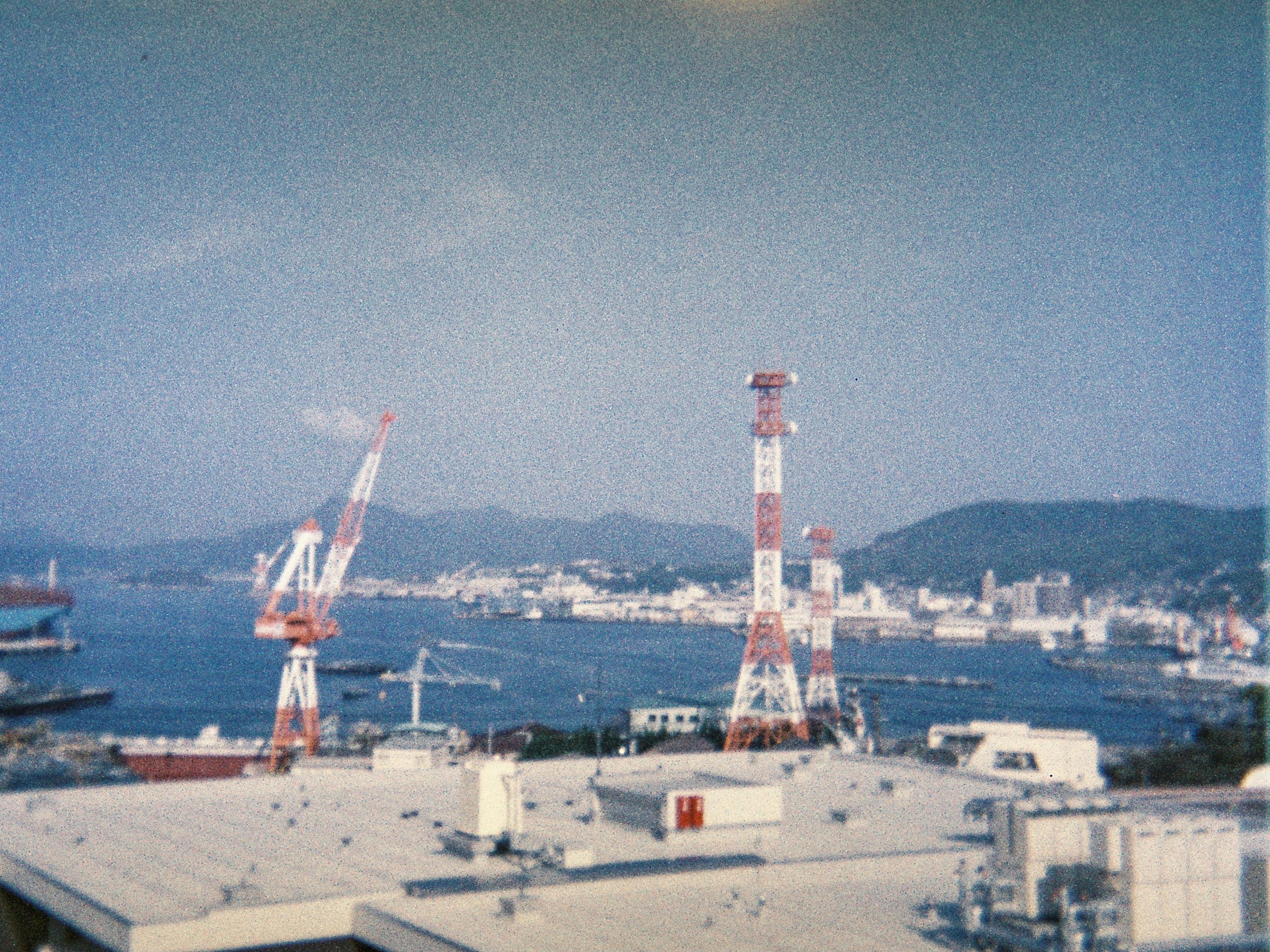 港にある赤と白のクレーンと周囲の山々を含む風景