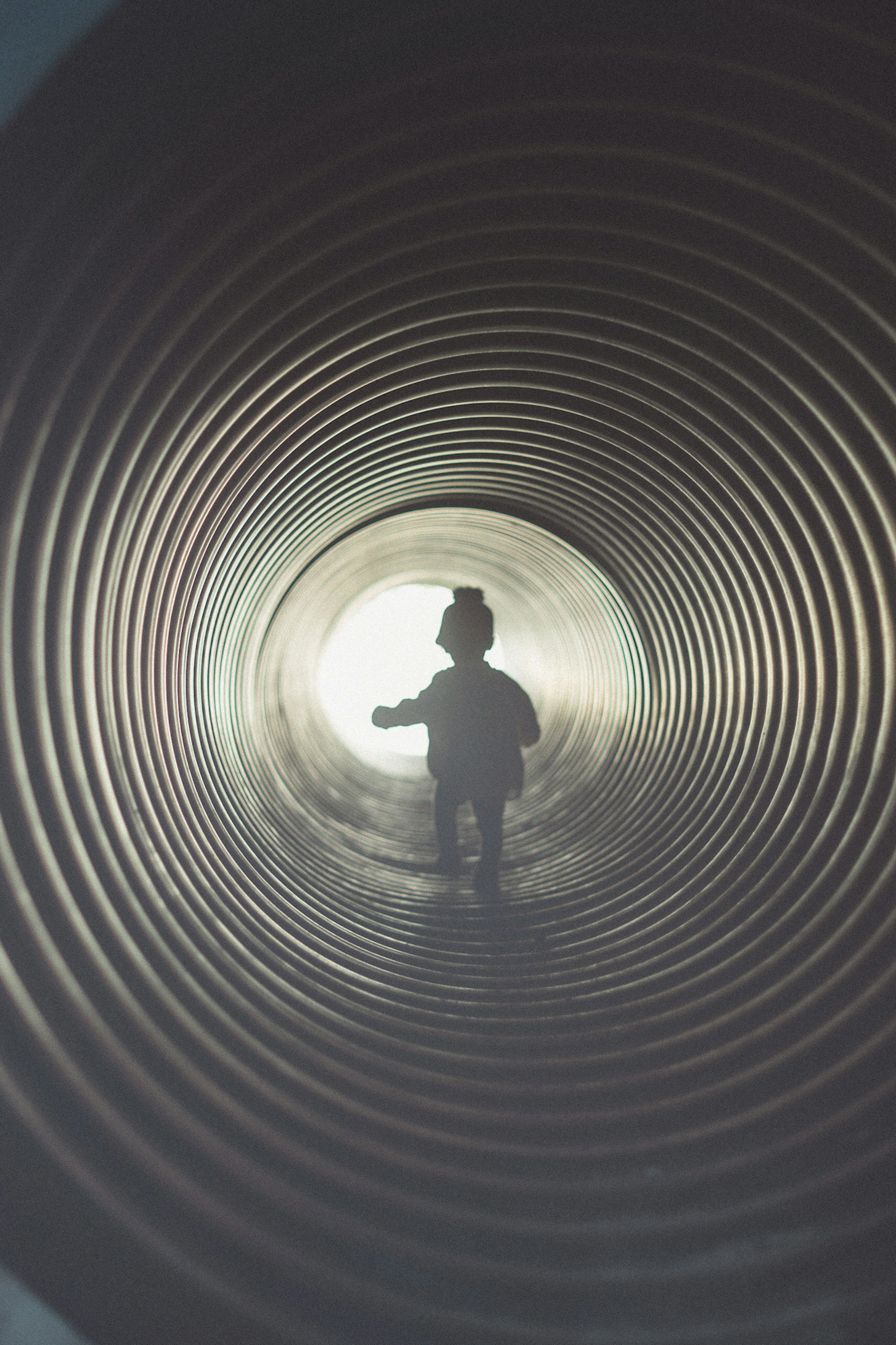 Silhouette of a child walking through a pipe with light effects