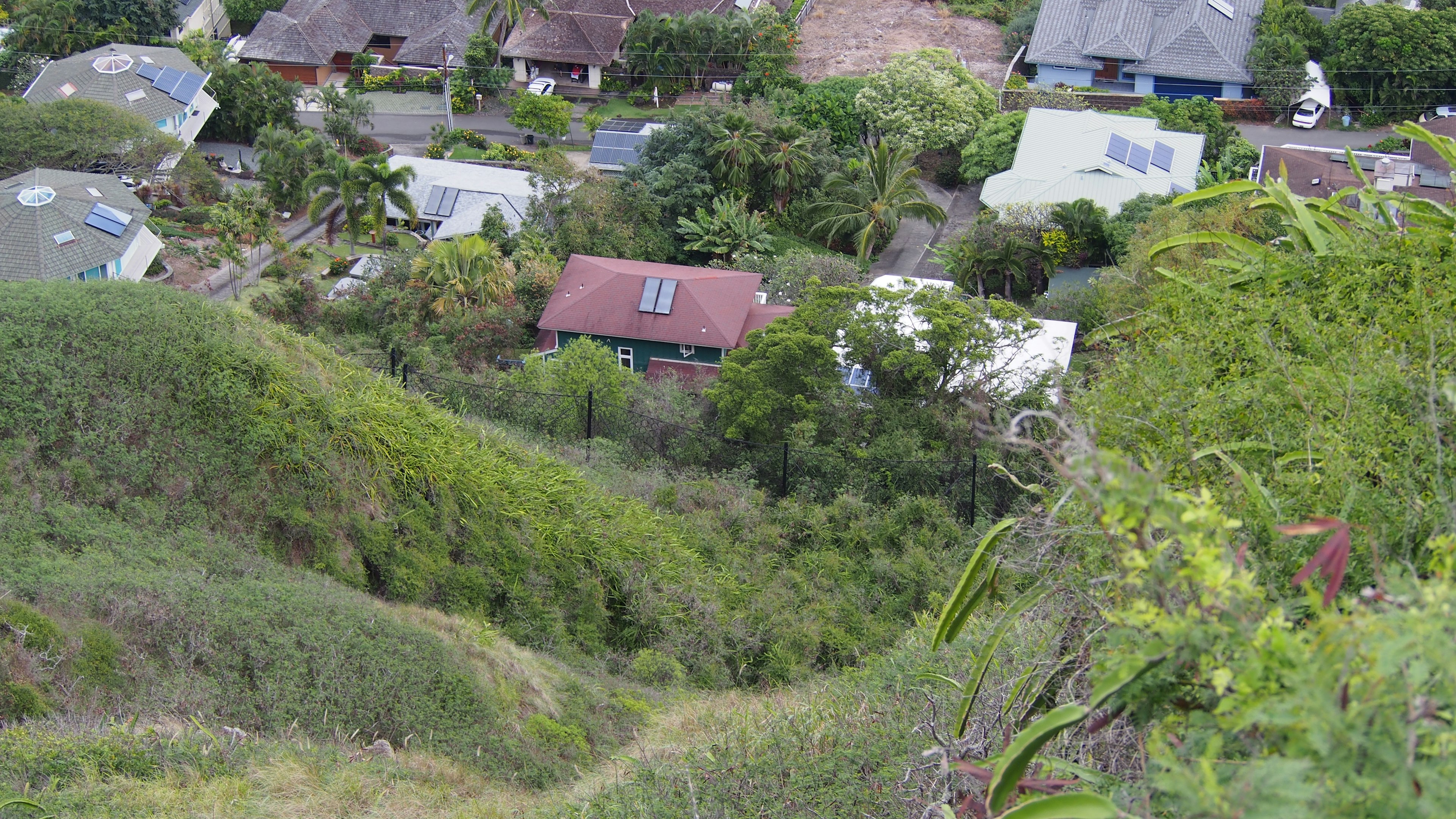 Una vista di un'area residenziale con colline verdi casa con tetto rosso e natura circostante