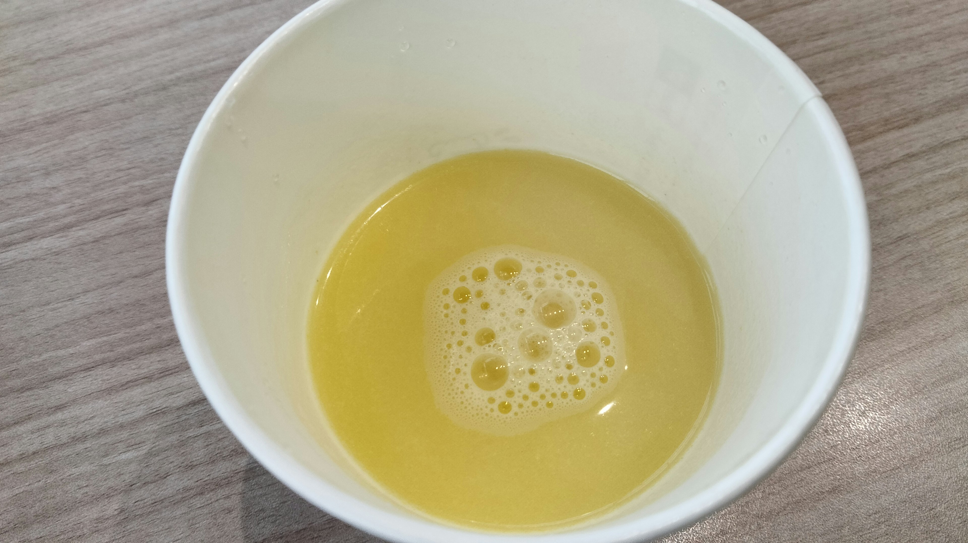 Yellow liquid with bubbles in a white cup