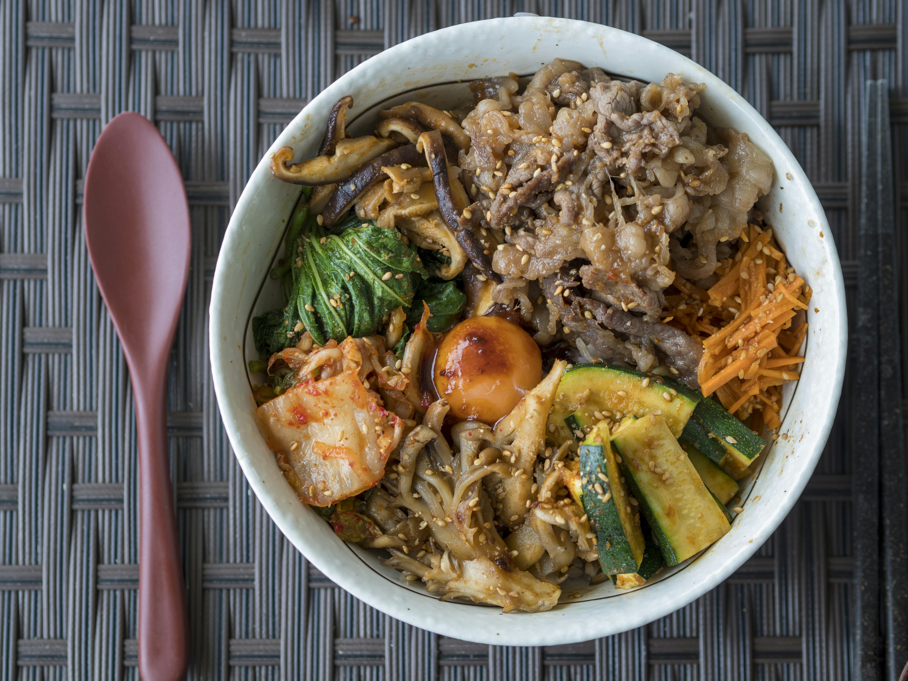 A bowl of Korean bibimbap with assorted vegetables and side dishes