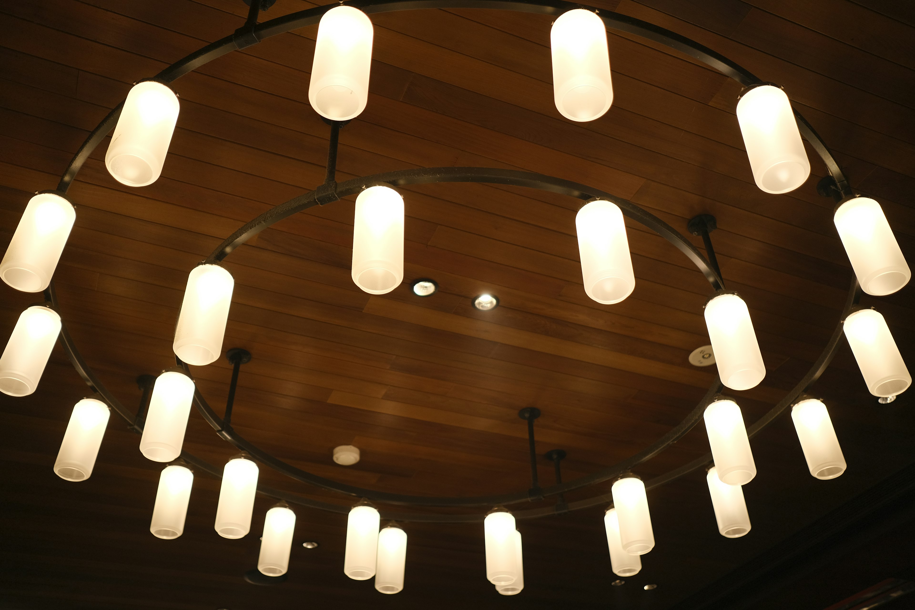 Lampadario circolare con paralumi bianchi appesi al soffitto in legno