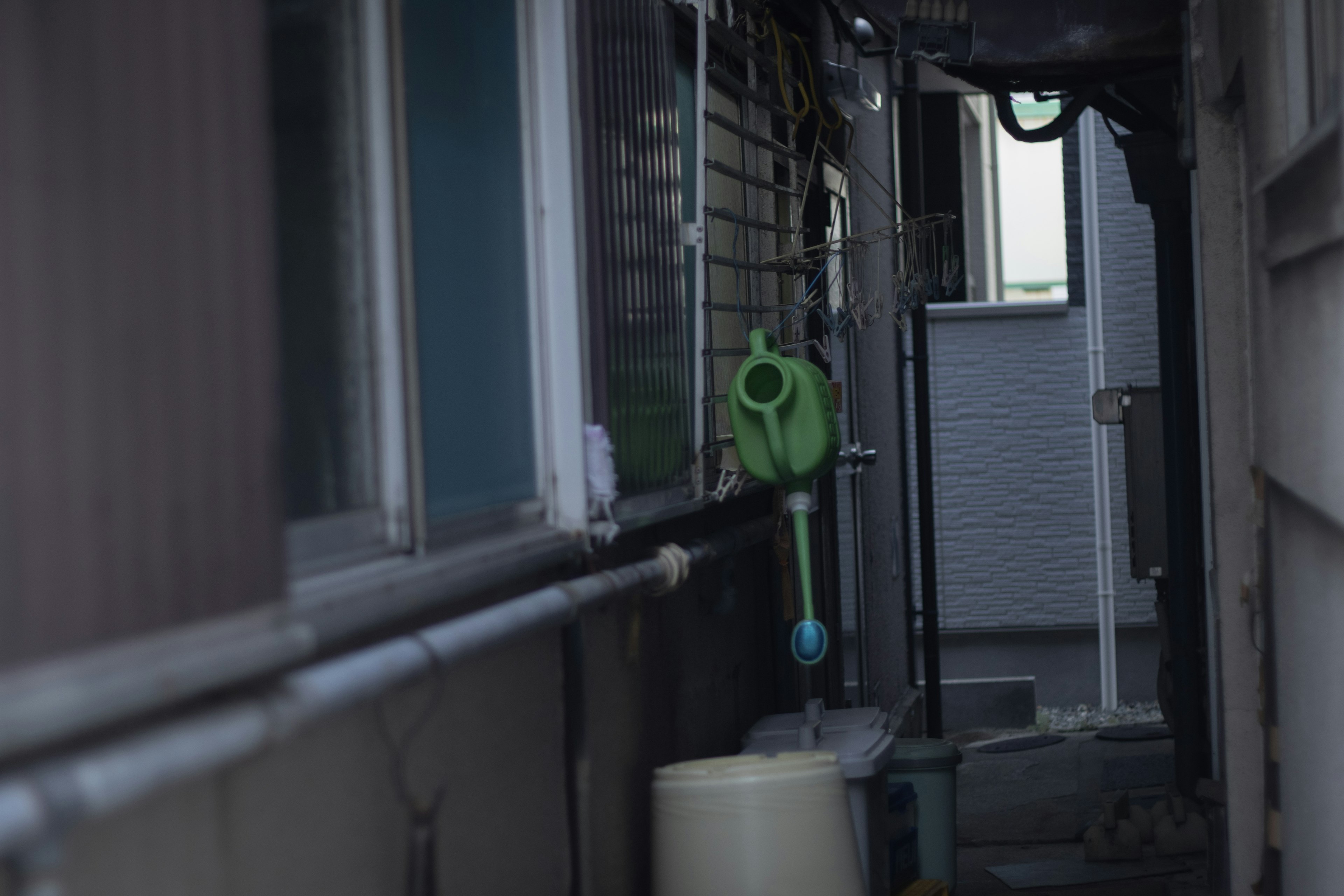 Narrow alleyway featuring a green watering can and a white container