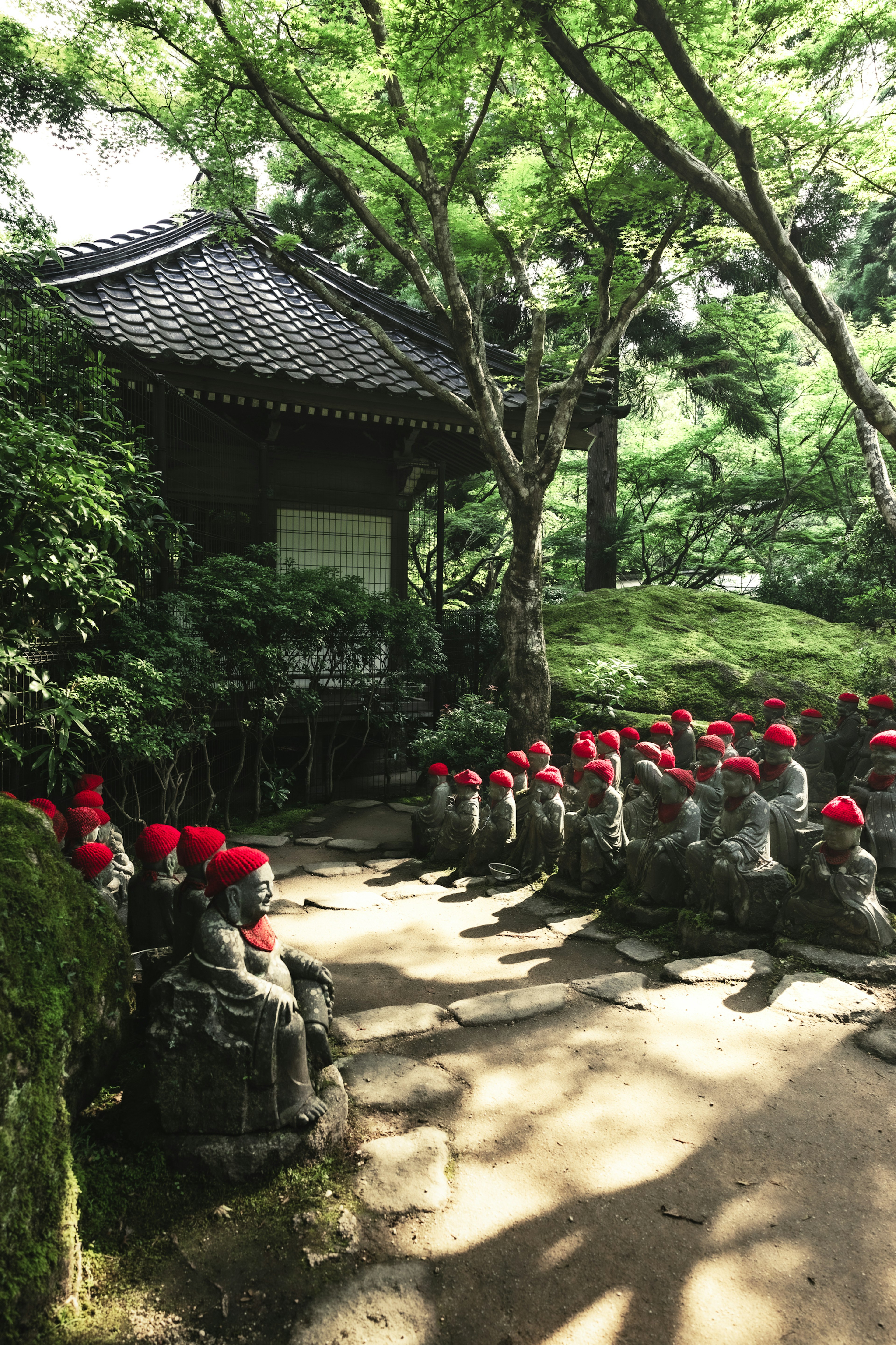 Escena de jardín con estatuas de piedra que llevan sombreros rojos